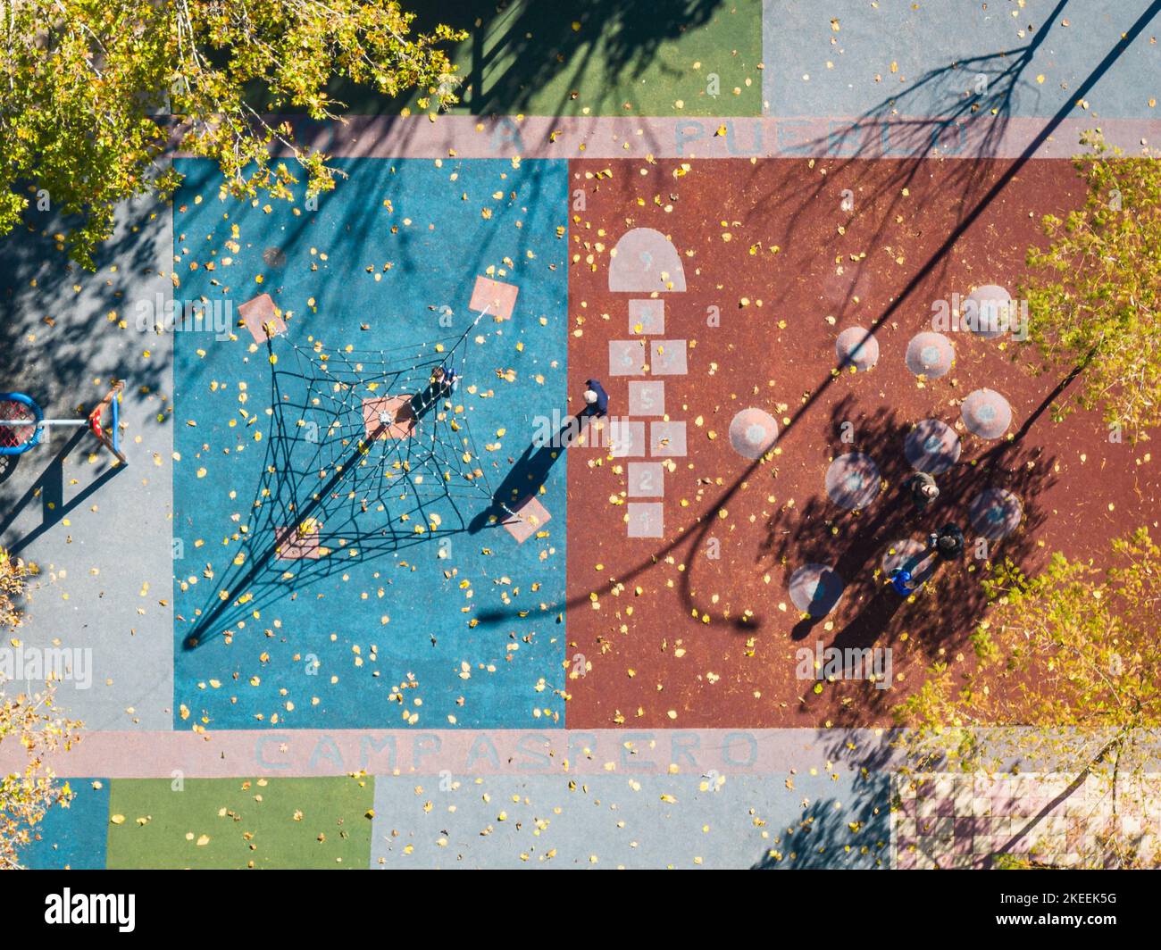 Vista aerea di un colorato parco giochi al crepuscolo, con le ombre delle diverse strutture e inidentificabili adulti e bambini. Foto Stock