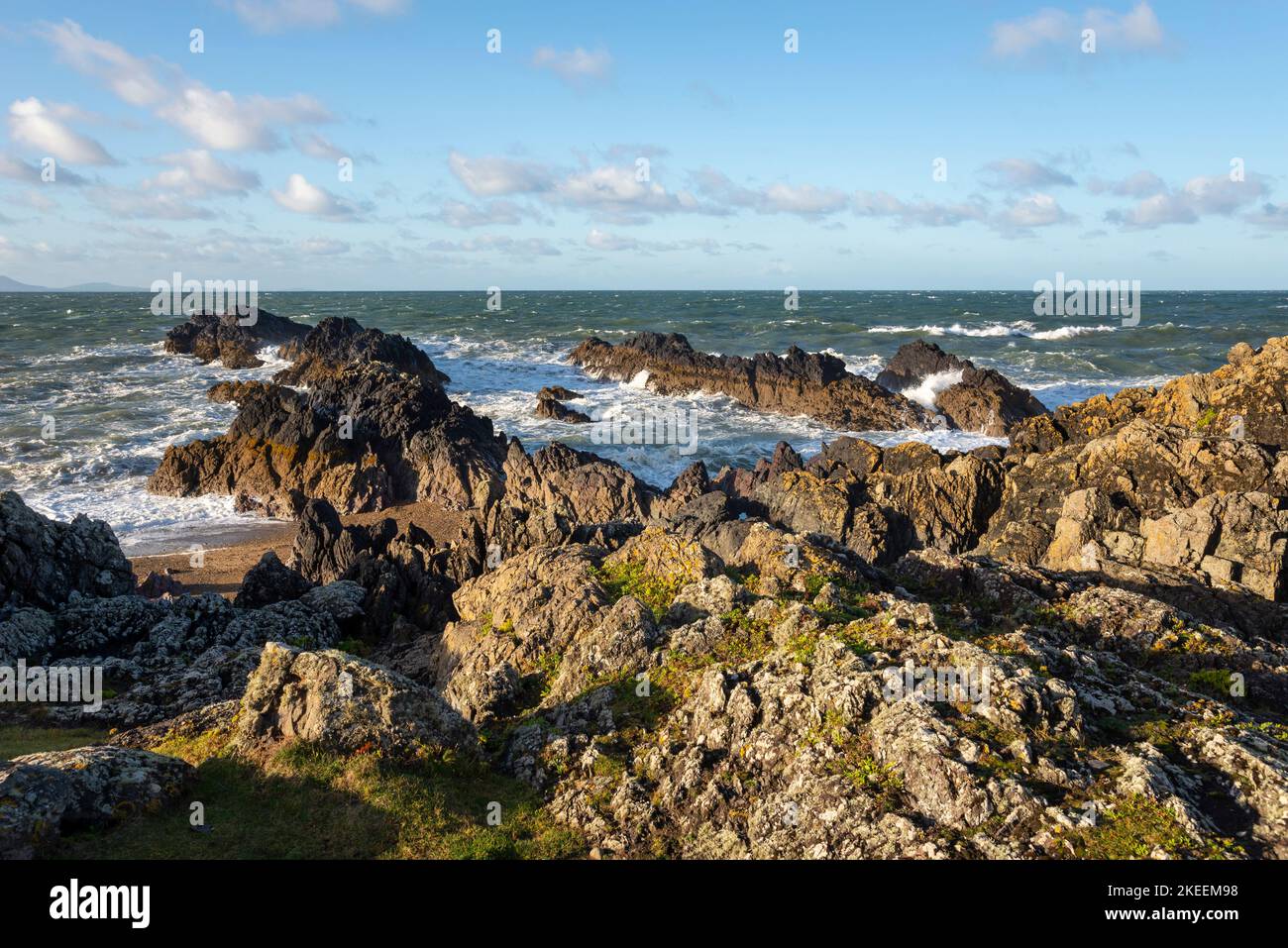 Costa rocciosa alla punta di Llanddwyn Island, Anglesey, Galles del Nord. Foto Stock
