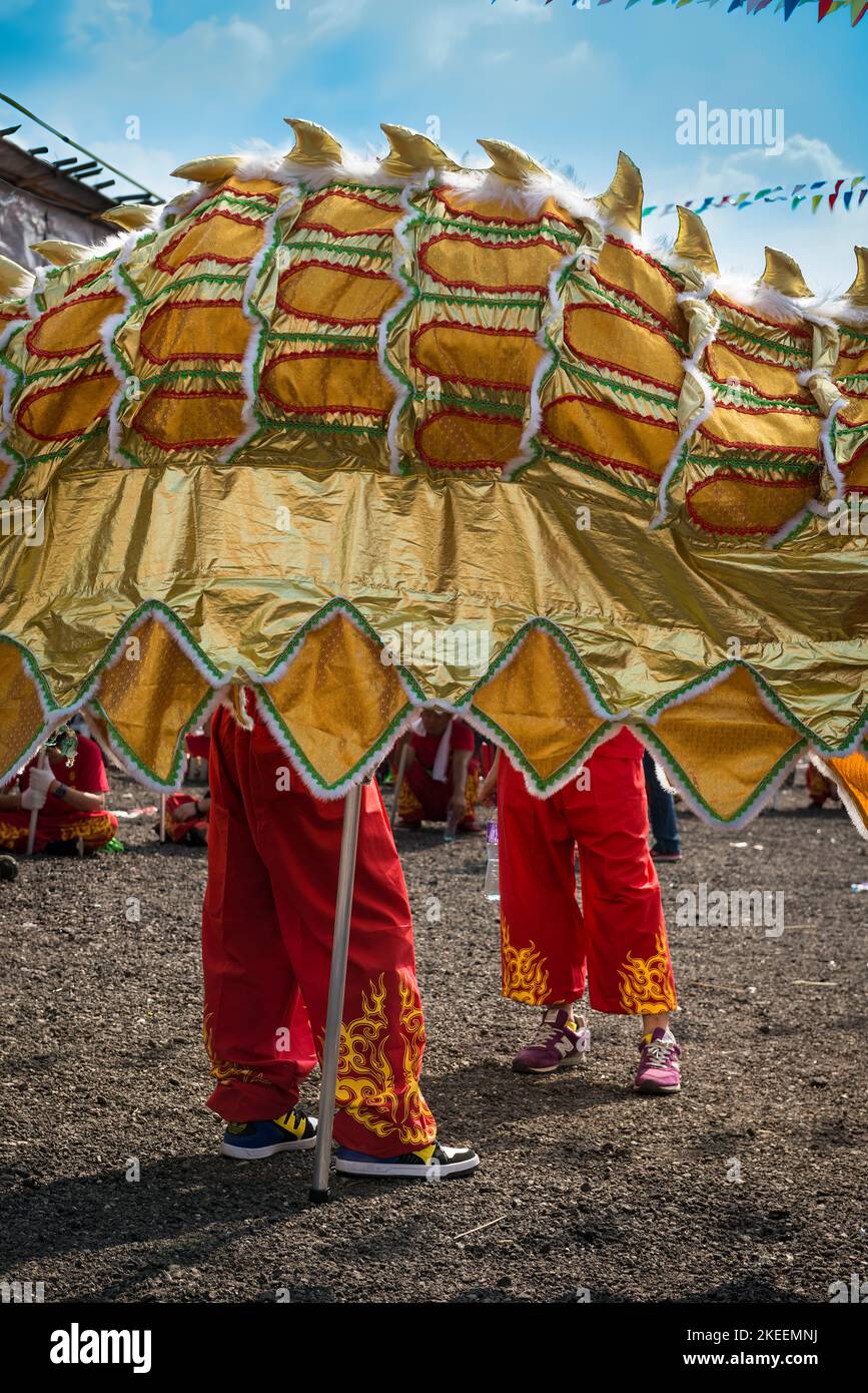 I membri della squadra di ballo del drago attendono la loro esecuzione con una sezione del burattino gigante presso il sito decennale del festival da Jiu, Kam Tin, Hong Kong, 2015 Foto Stock