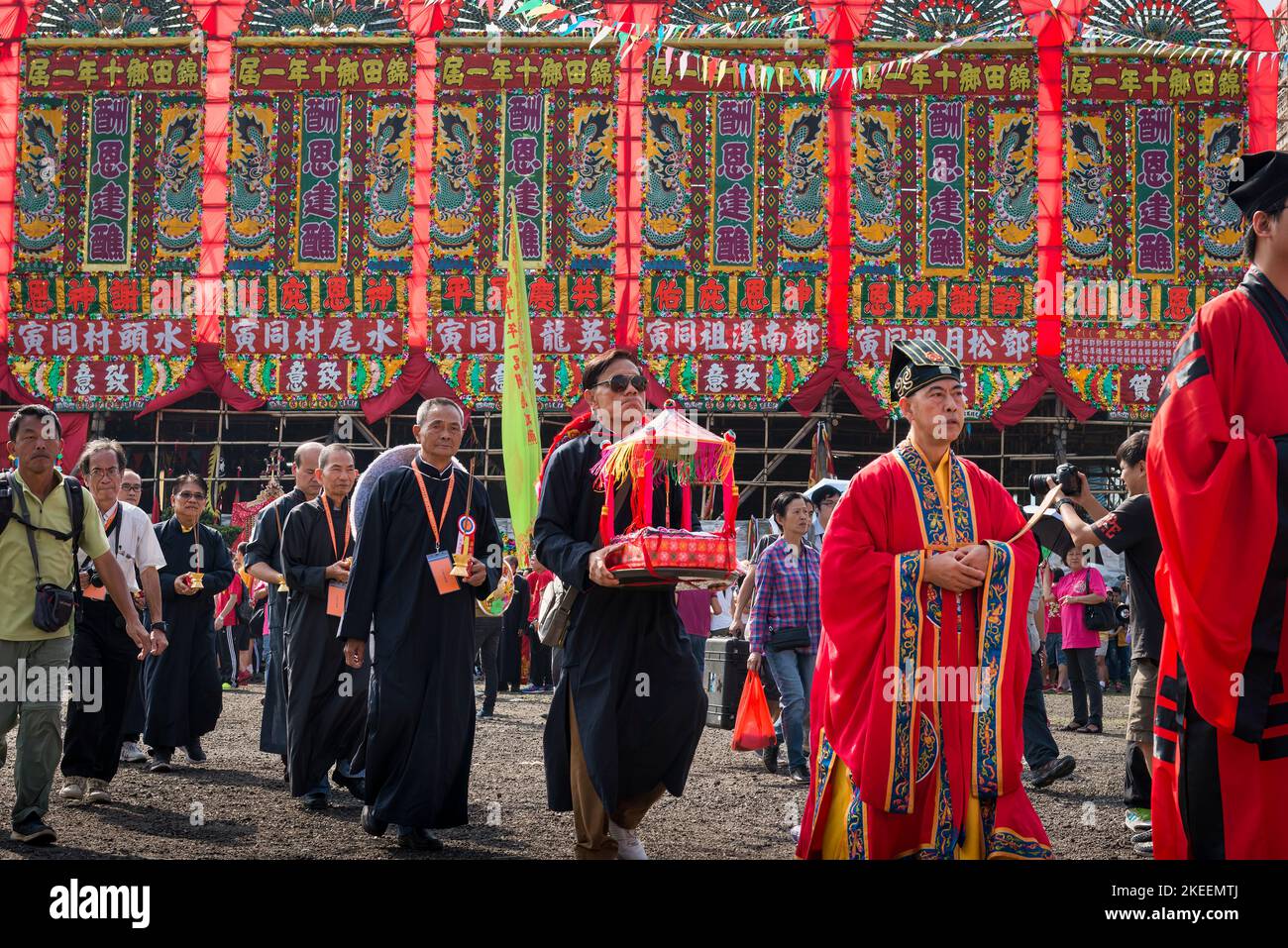 I sacerdoti taoisti dal colore rosso guidano gli anziani del villaggio in una processione rituale attraverso il sito decennale del festival da Jiu, Kam Tin, Hong Kong, 2015 Foto Stock