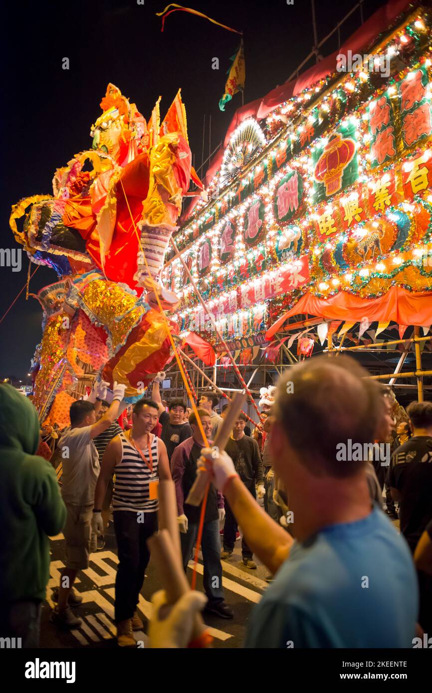 Un villager sostiene l'enorme effigie del re fantasma nella strada a Kam Tin di notte durante il decennale da Jiu festival, Hong Kong, 2015 Foto Stock