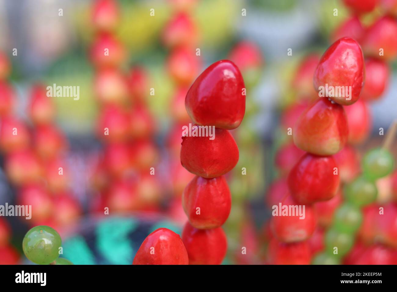 Caramella fragole e uva su spiedini con anguria sullo sfondo Foto Stock