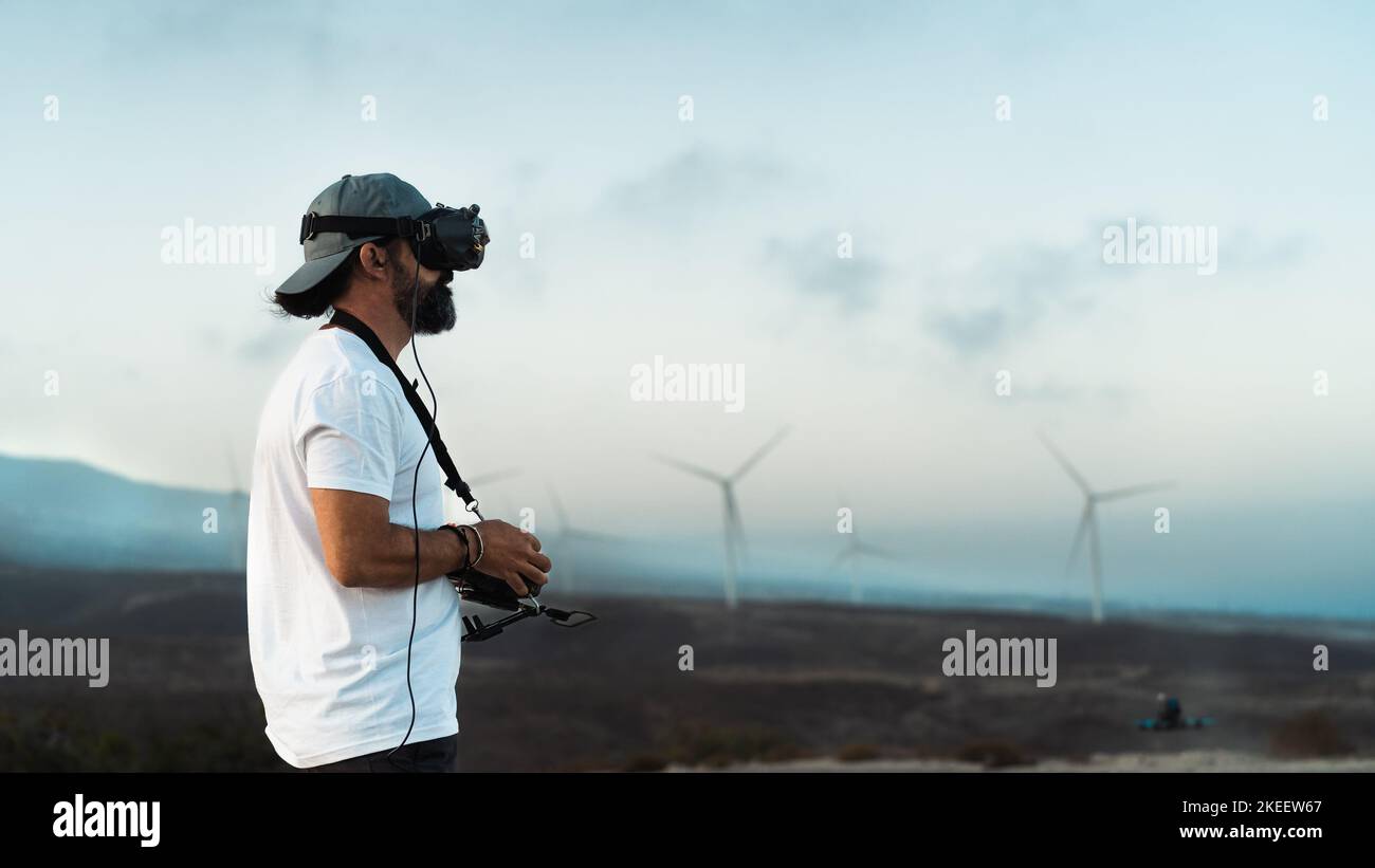 Ingegnere dei droni che utilizza la tecnologia di visualizzazione in prima persona nella farm di turbine - energia alternativa e concetto di ingegneria aerea Foto Stock Ingegnere dei droni che utilizza la tecnologia di visualizzazione in prima persona nella farm di turbine - energia alternativa e concetto di ingegneria aerea Foto Stock