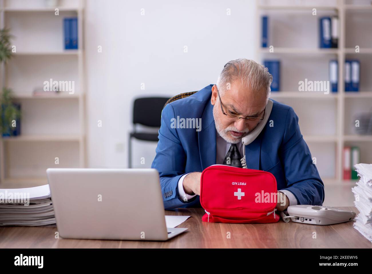 Il vecchio dipendente dell'uomo d'affari si sente male sul posto di lavoro Foto Stock