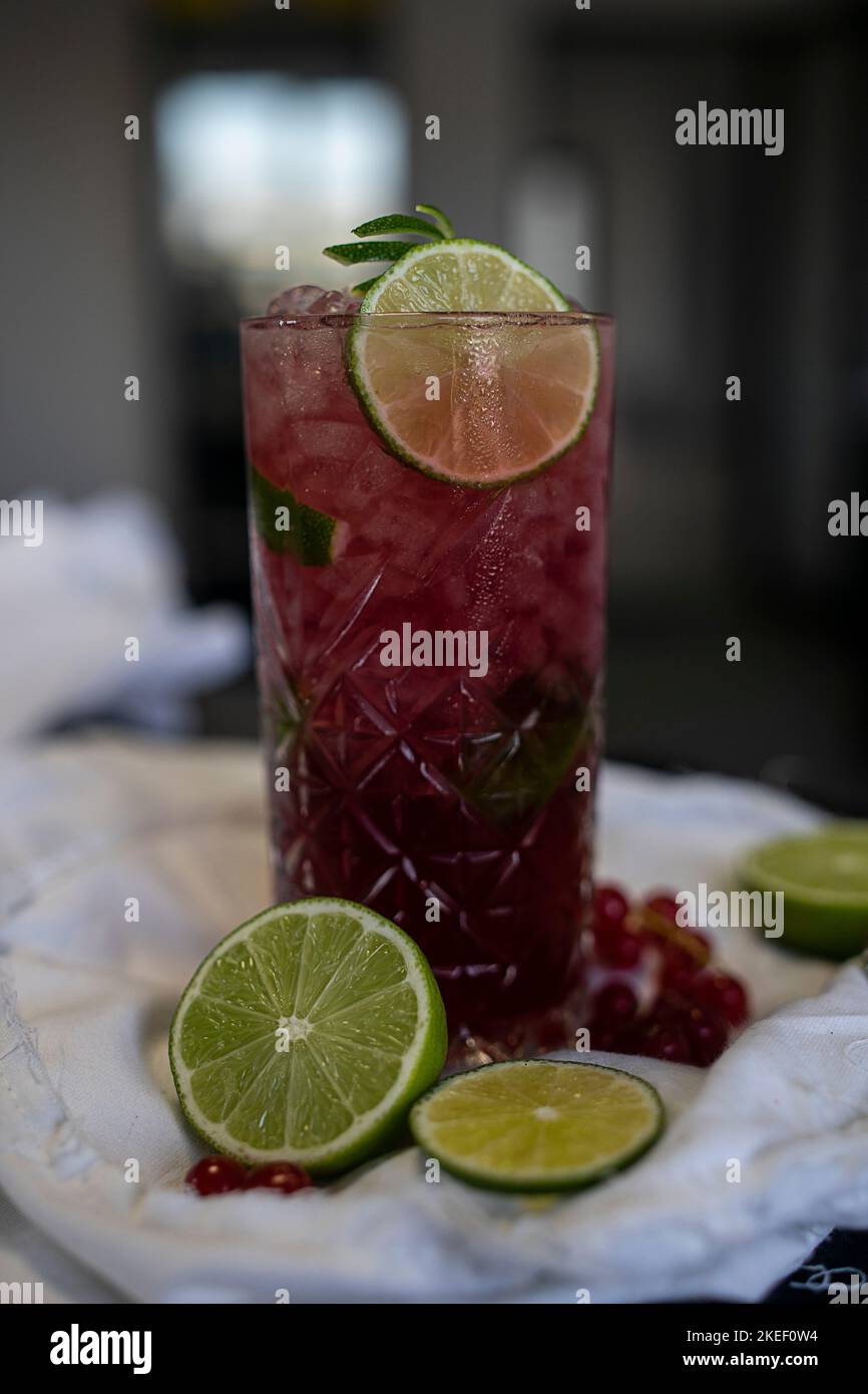Bicchiere da cocktail rosso con frutto della passione e vodka, aromatizzato con lavanda e ghiaccio tritato. Foto Stock