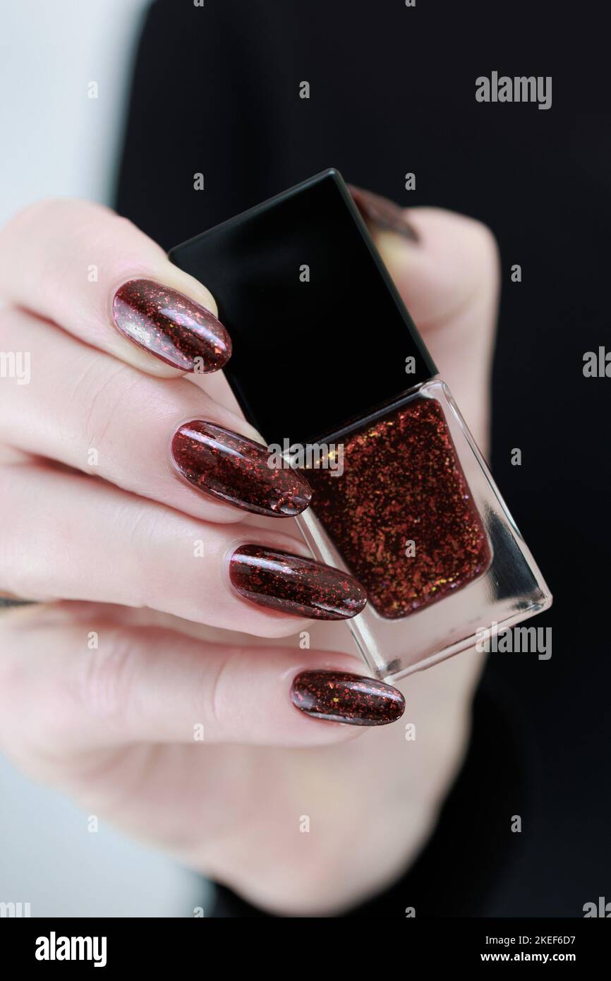 Donna mano con unghie lunghe e una bottiglia di scuro smalto rosso bordeaux per  unghie Foto stock - Alamy