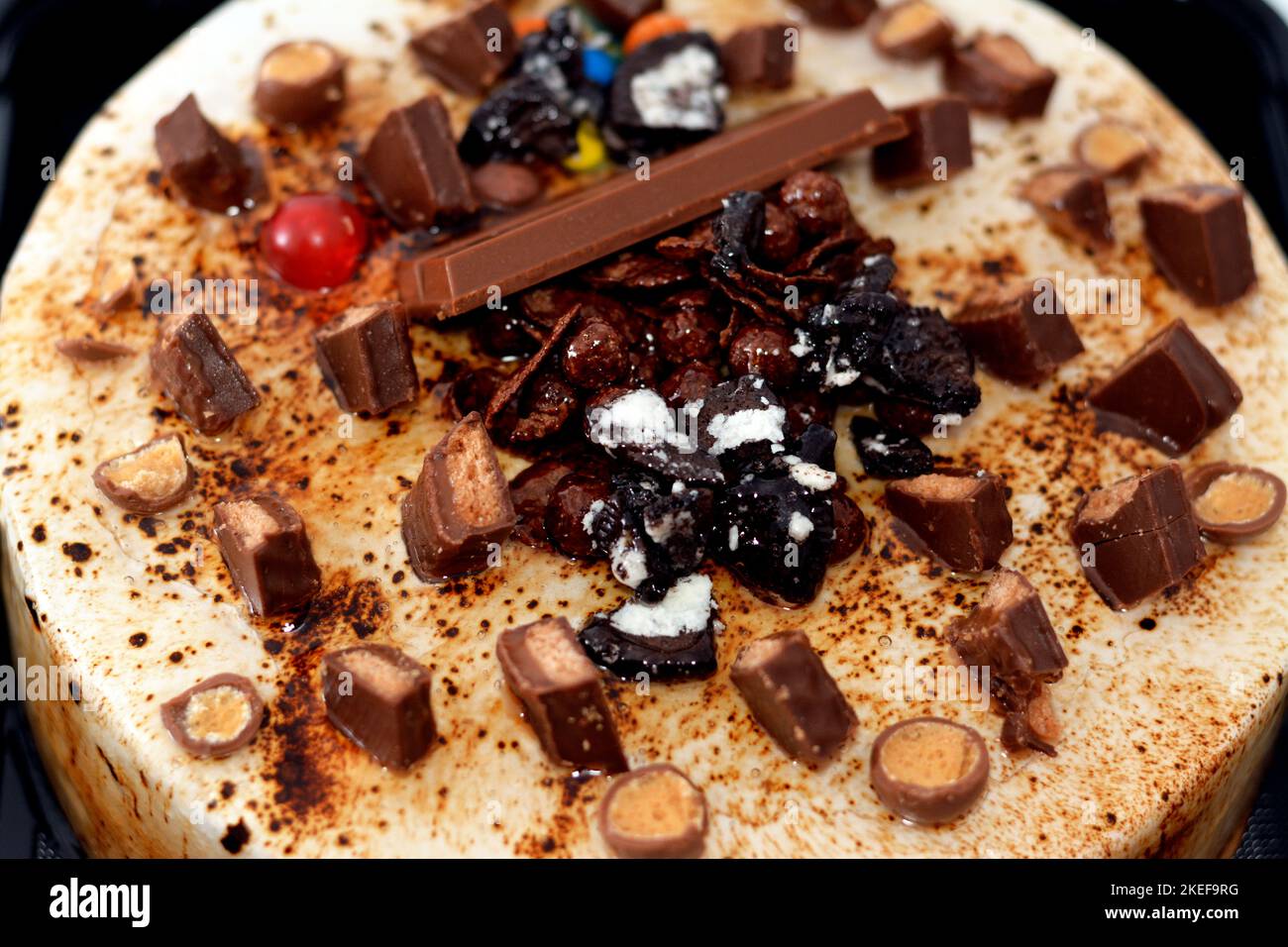 Torta festosa al cioccolato al caramello ricoperta di caramello e panna montata, farcita con crema alla vaniglia e noci, e decorata con diversi tipi di choc Foto Stock