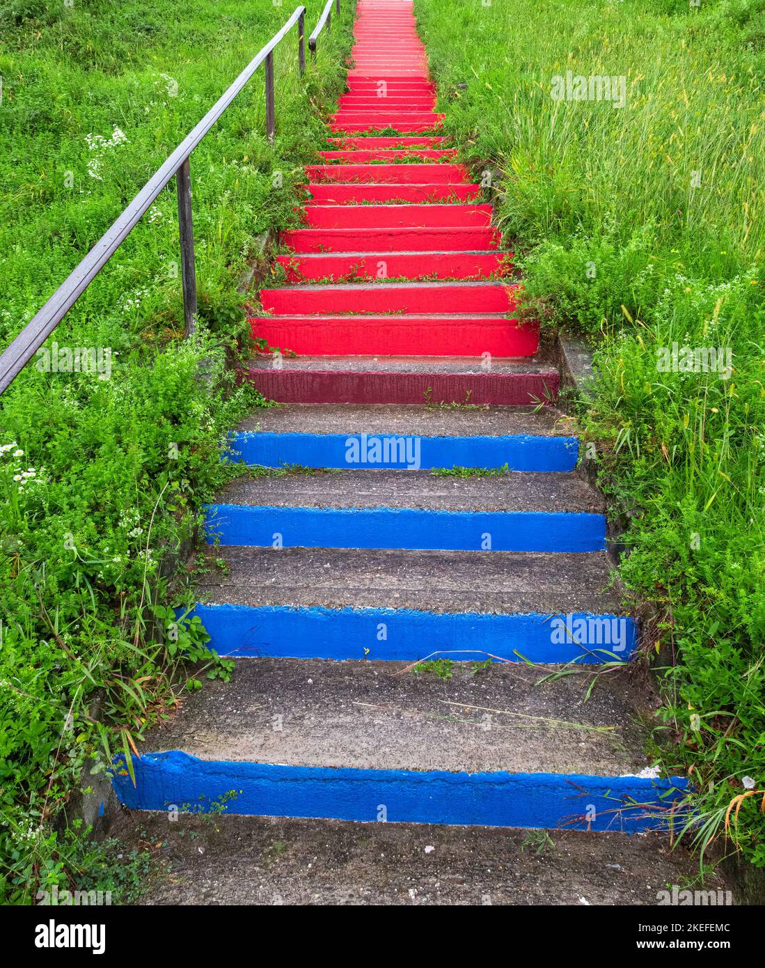Scalini in pietra nei colori rosso e blu che si arrampicano sul prato Foto Stock