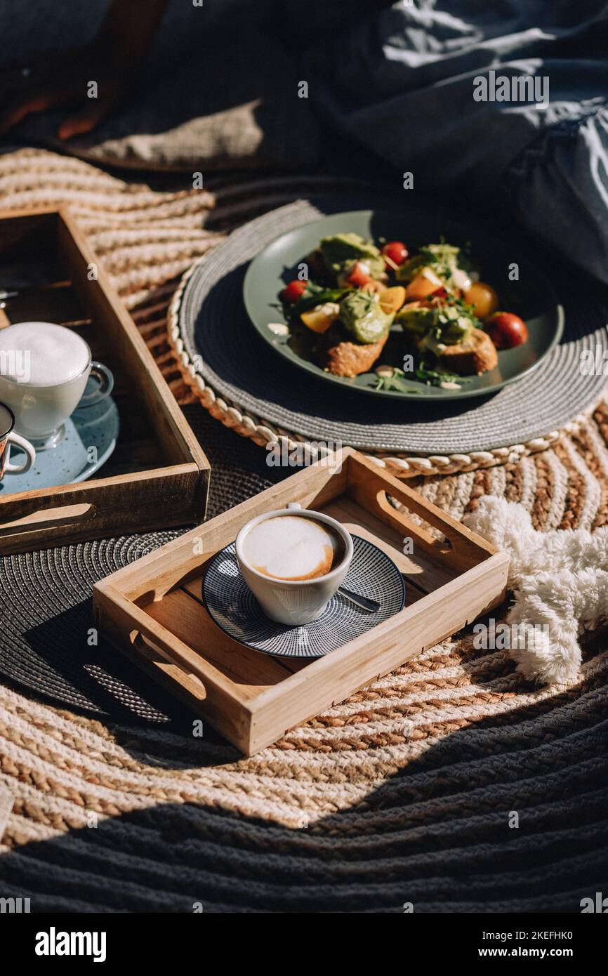 Un colpo verticale di tavole di legno con cappuccini e un piatto di brindisi di verdure all'aperto Foto Stock