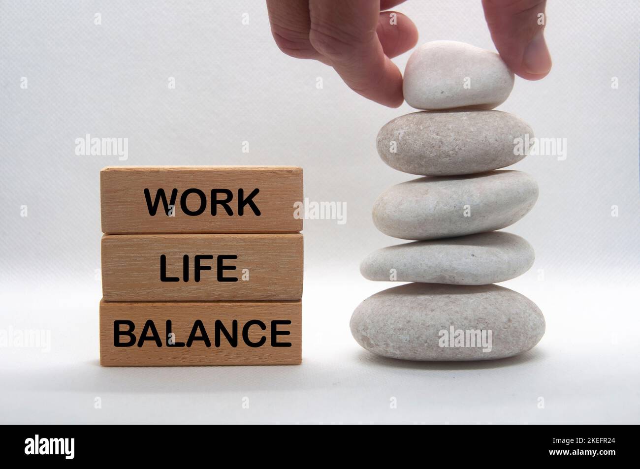 Testo di equilibrio di vita di lavoro su blocchi di legno con pietre di zen di impilamento a mano. Concetto di cultura del lavoro. Foto Stock