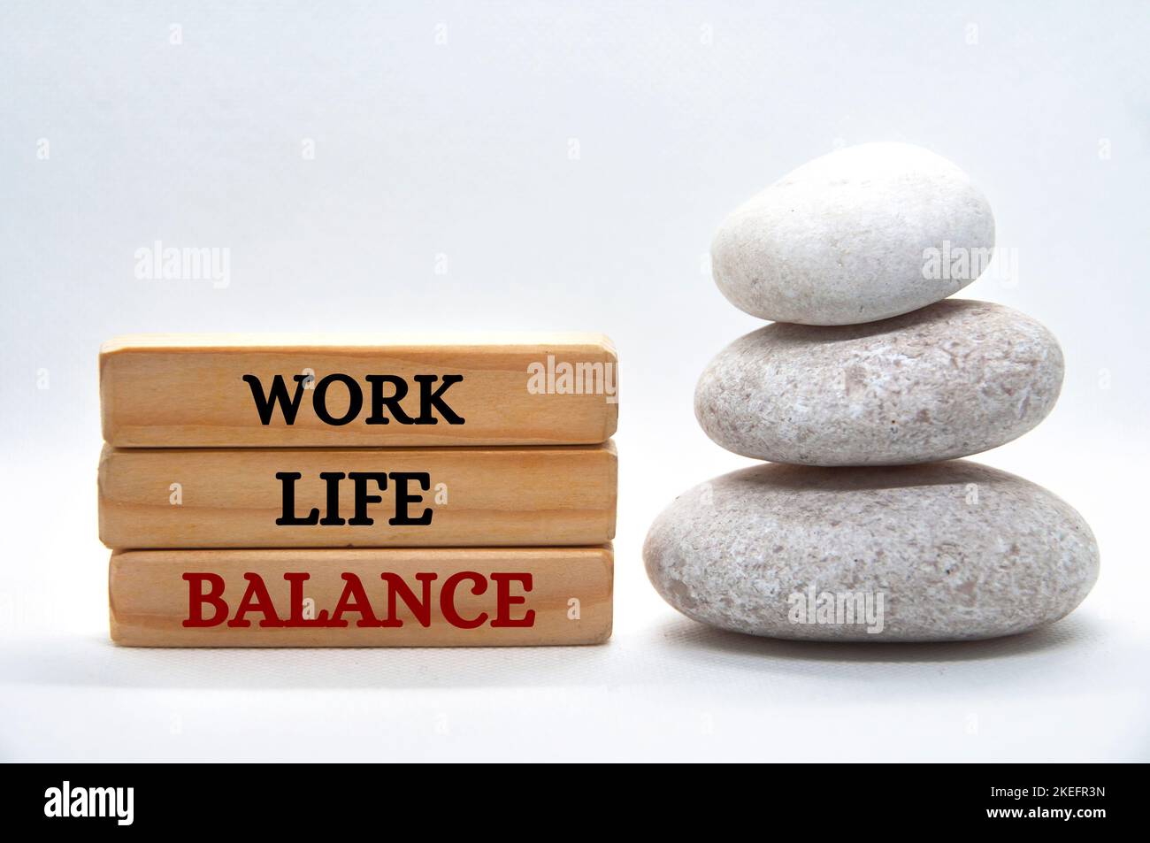 Vita lavorativa testo di equilibrio su blocchi di legno con pietre zen equilibrate. Concetto di cultura del lavoro Foto Stock