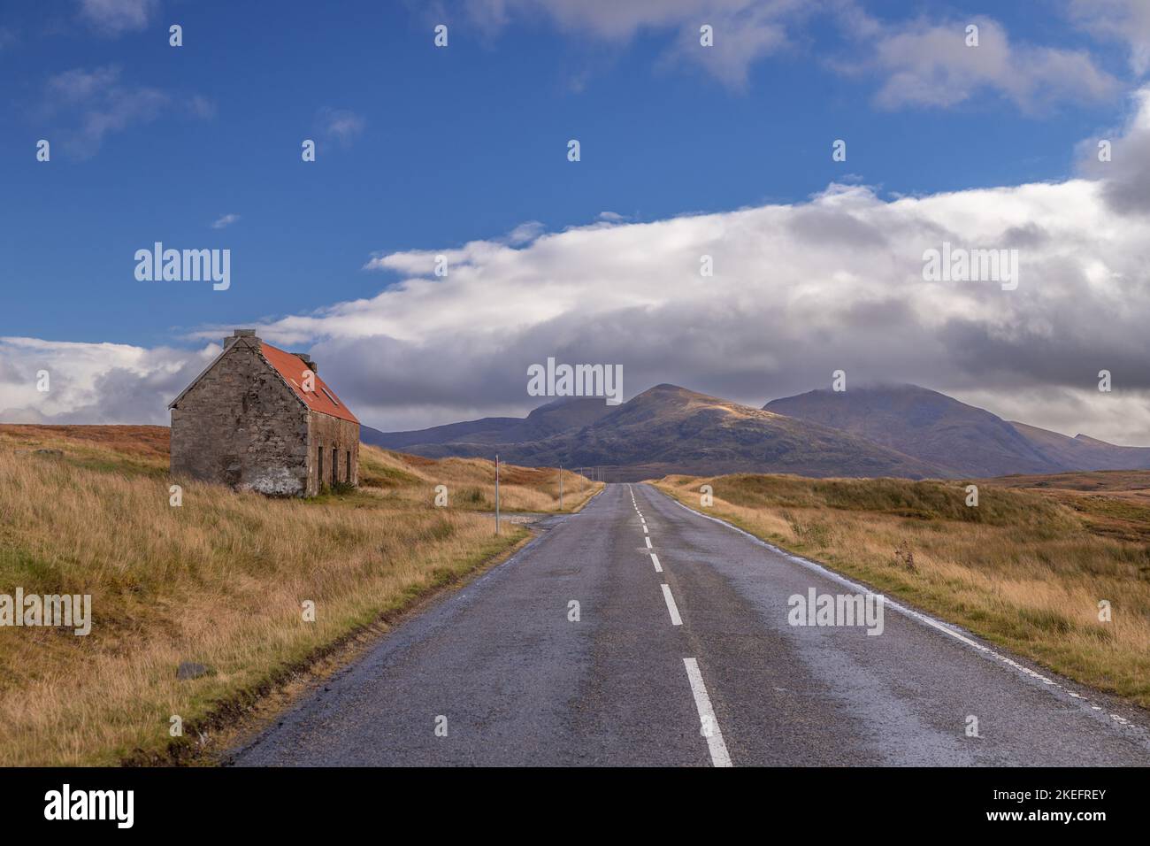 Strada attraverso gli altopiani scozzesi con cottage abbandonato Foto Stock