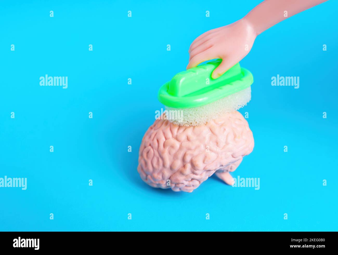 Giocattolo lavaggio a mano una figurina cervello umano in miniatura con una spugna. Concetto creativo di lavaggio del cervello. Foto Stock
