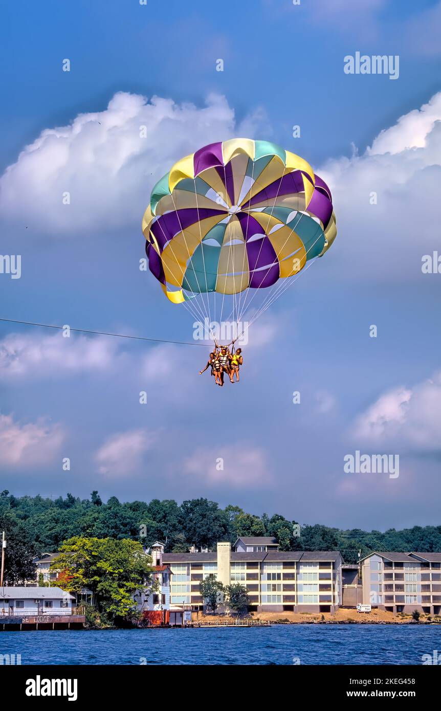 Tre persone che usano uno scivolo sono viste parasailing sul Lago degli Ozarks nel Missouri Foto Stock