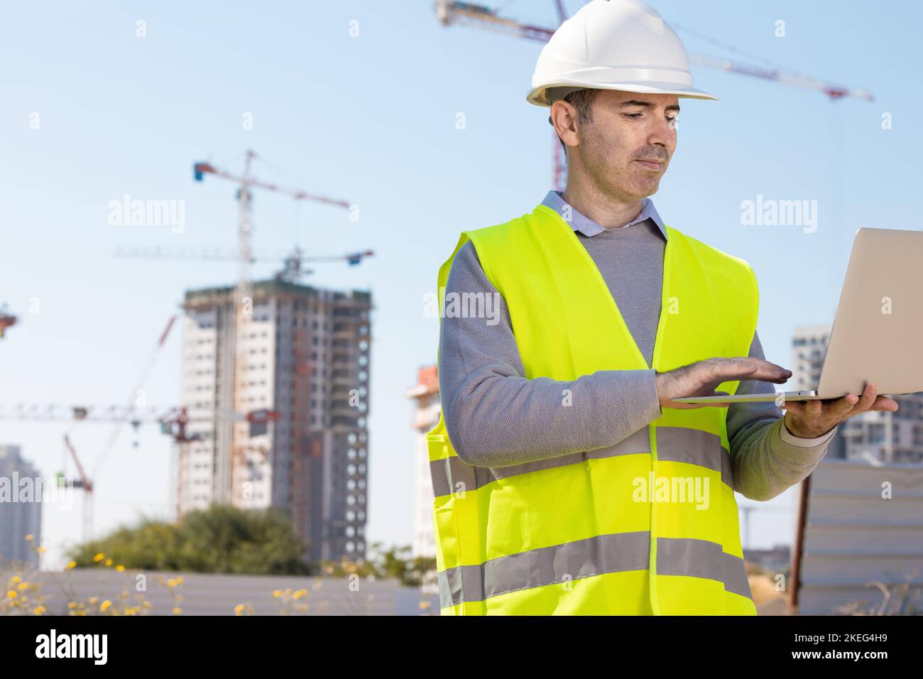 Costruttore professionista in piedi con notebook davanti al cantiere Foto Stock