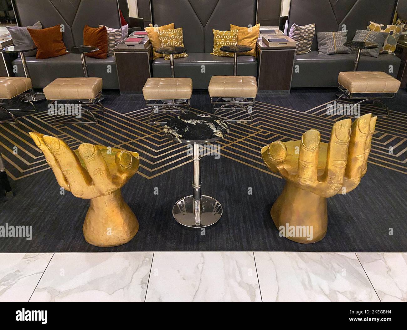 Sedie dorate a forma di mano e altri arredi moderni nella lobby dell'hotel Foto Stock