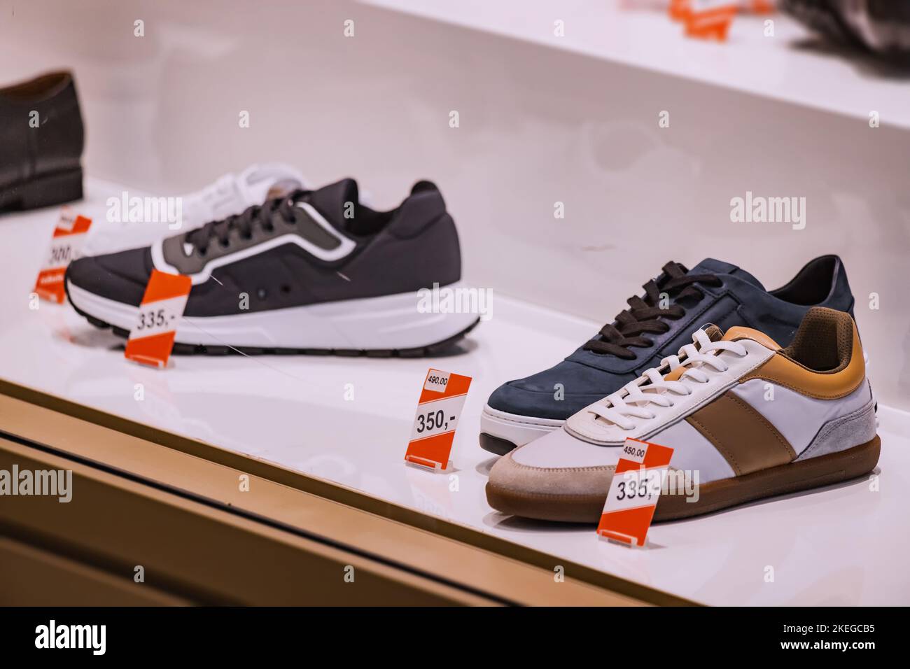 Scarpe e sneakers alla moda e contemporanee nella vetrina del negozio di calzature Foto Stock