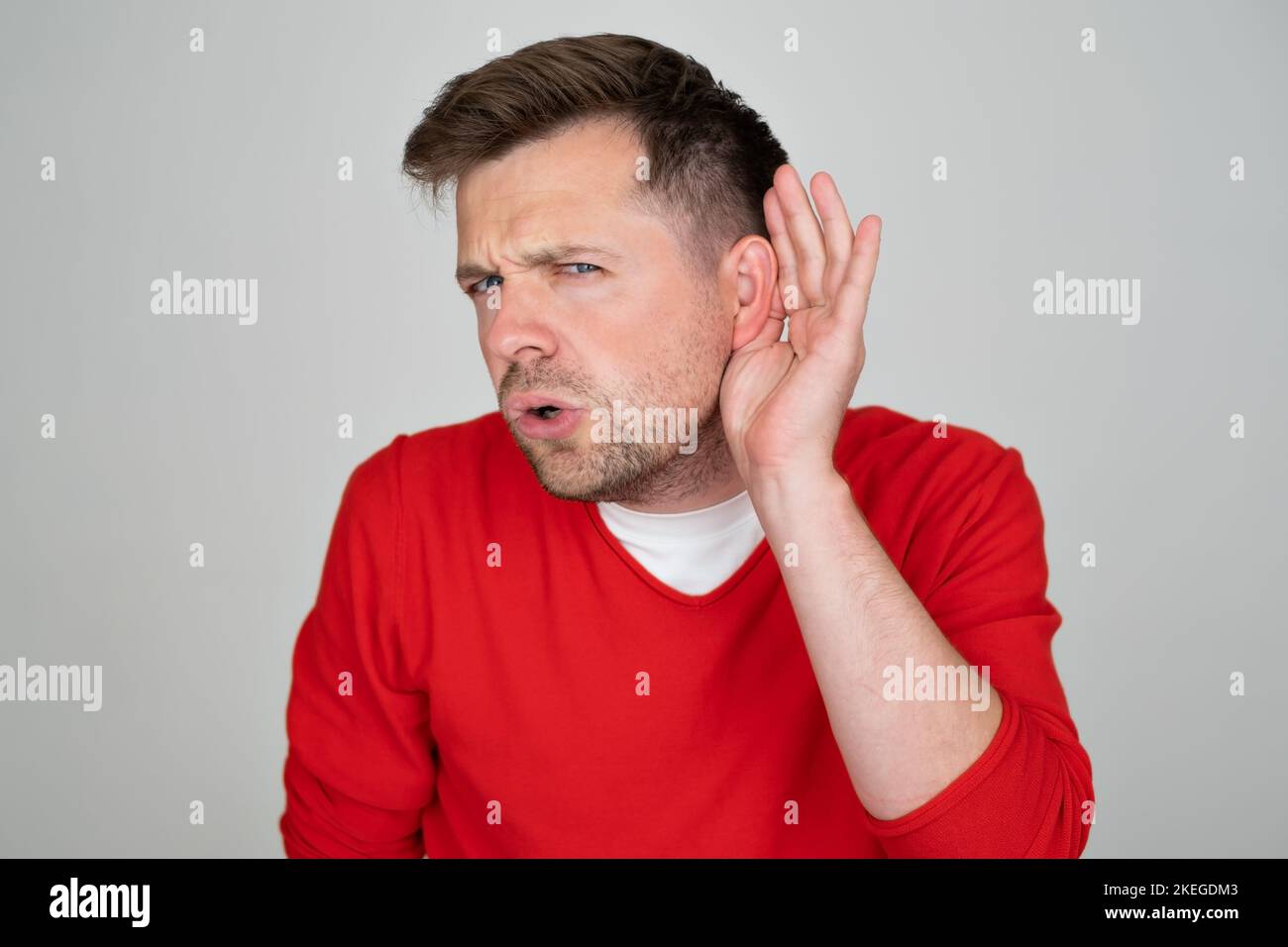 Poco felice di sentire l'uomo che mette mano sull'orecchio chiedendo a qualcuno di parlare in su Foto Stock
