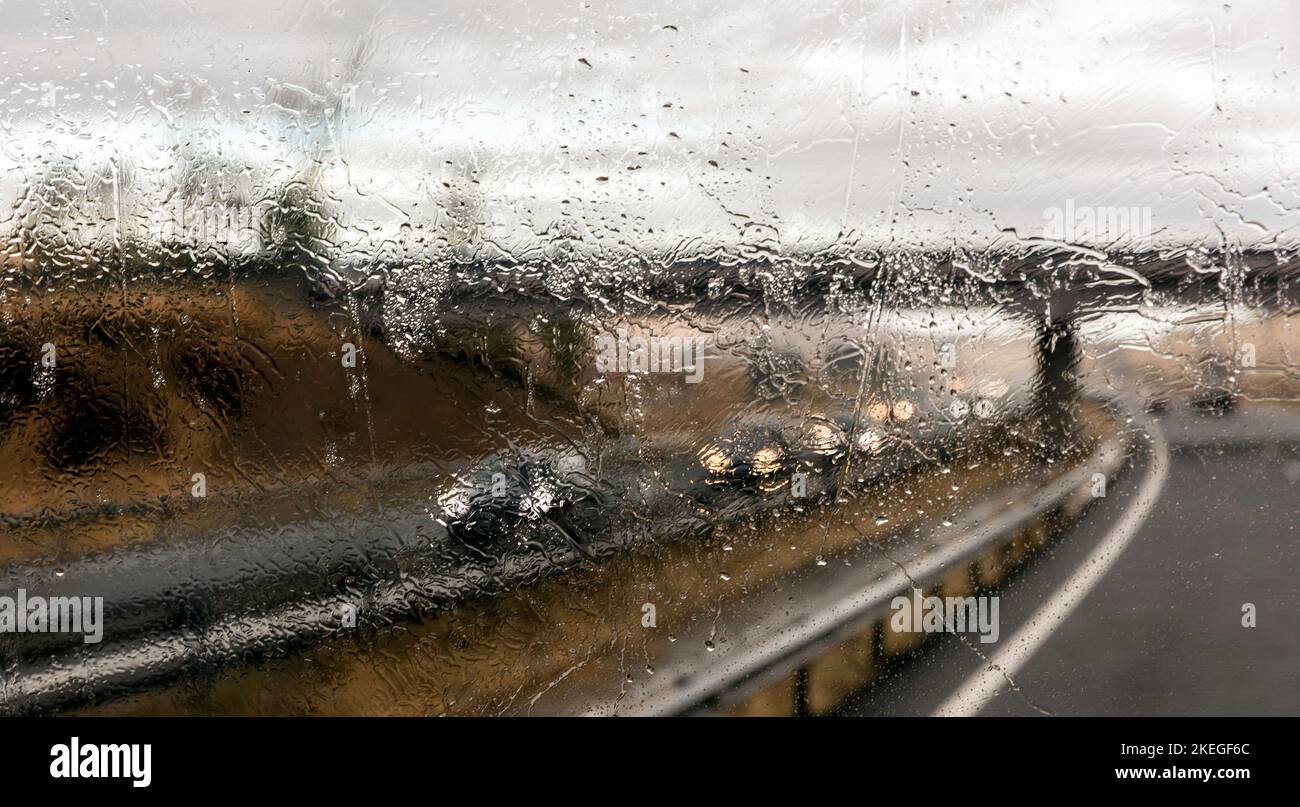 Vista attraverso il parabrezza del traffico in autostrada sotto la pioggia Foto Stock