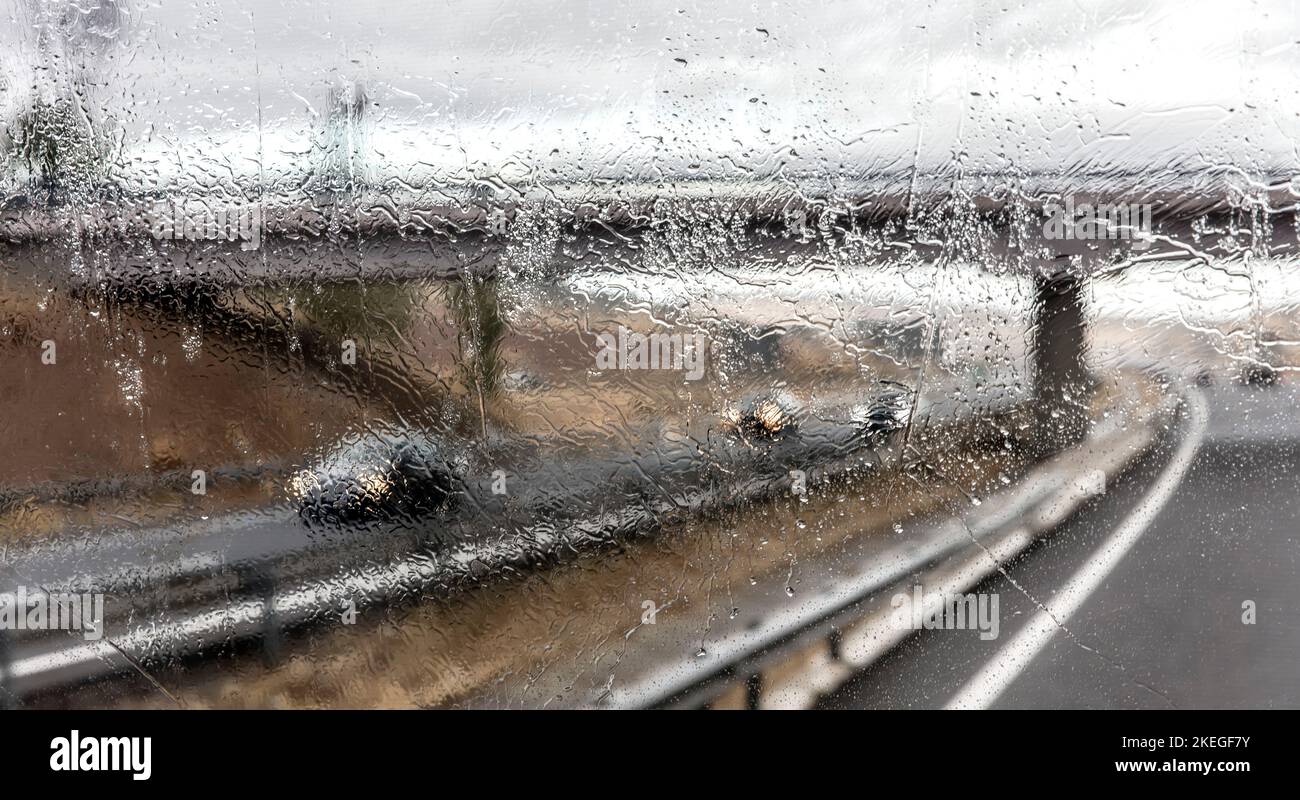 Vista attraverso il parabrezza del traffico in autostrada sotto la pioggia Foto Stock
