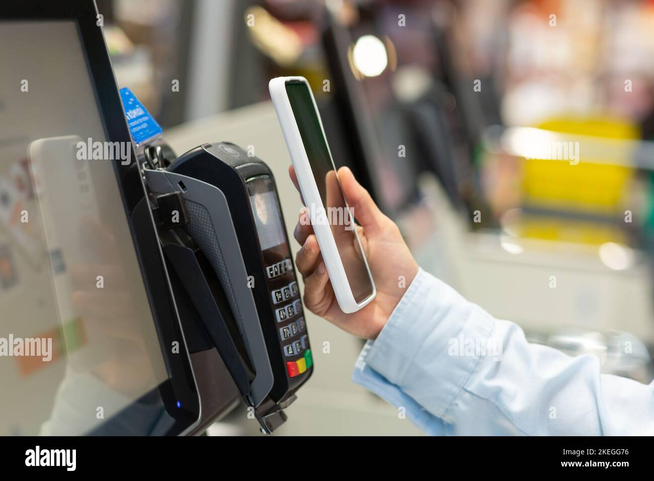 Closeup Woman Counter Acquista pagamento elettronico supermercato smartphone mano femmina con un telefono cellulare a pagamento per acquisti in negozi Contactless NFC Terminal Closeup card reader. Foto Stock