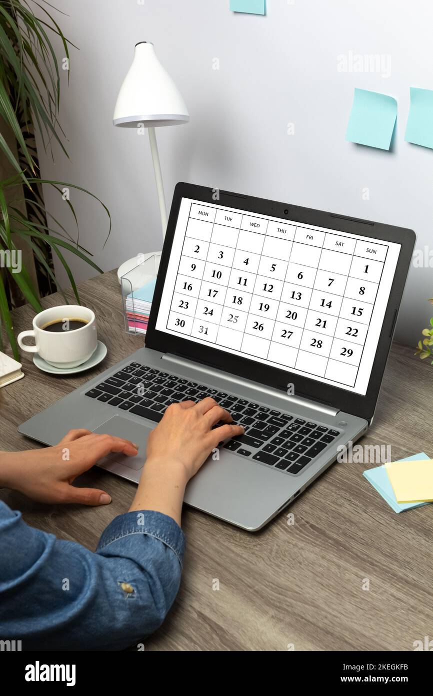 Donna che pianifica riunioni aziendali mensili, pianificazione e obiettivi utilizzando il calendario sul notebook. Foto Stock