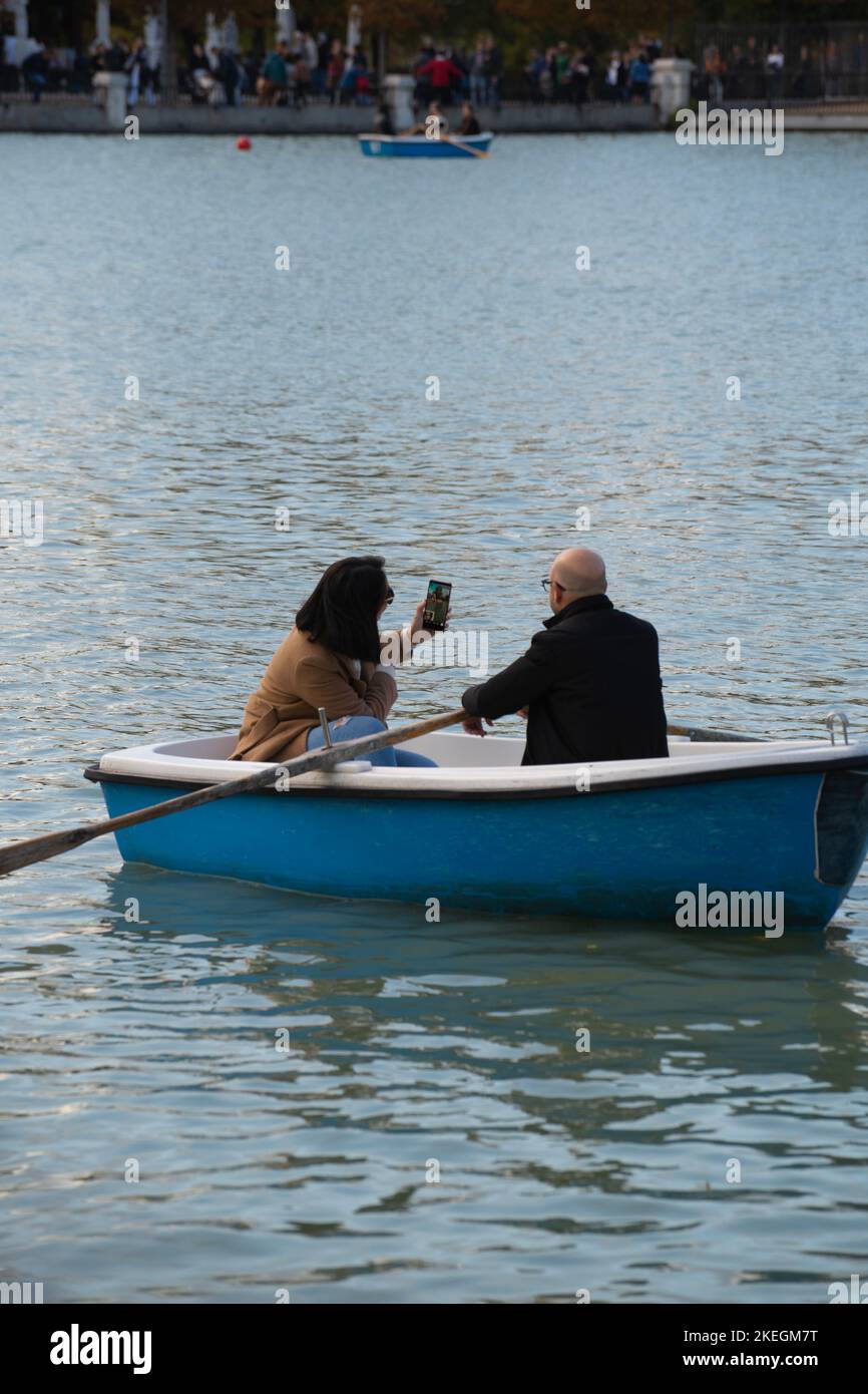 Coppia di adulti che prendono una videoconferenza selfie su una barca in un lago al parco retiro di Madrid Foto Stock
