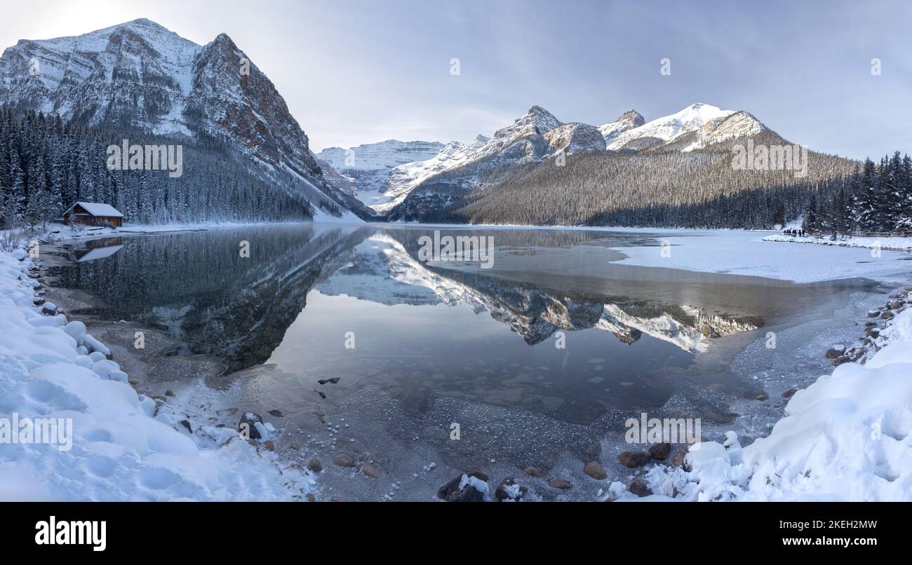 Lake Louise Panorama Banff National Park. Cime innevate delle Montagne Rocciose calme riflesso d'acqua soleggiata giornata fredda invernale paesaggio panoramico delle Montagne Rocciose canadesi Foto Stock
