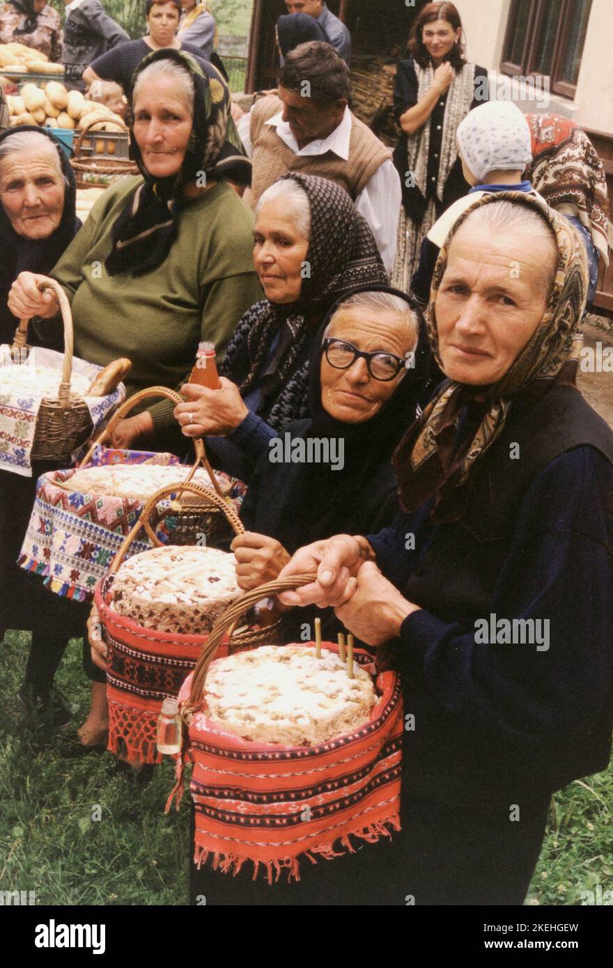 Contea di Hunedoara, Romania, 2003. La comunità di Momarlani seppellendo i loro morti nel cortile, secondo la loro tradizione. Donne con cesti di koliva, un piatto commemorativo per l'anima dei morti. Foto Stock