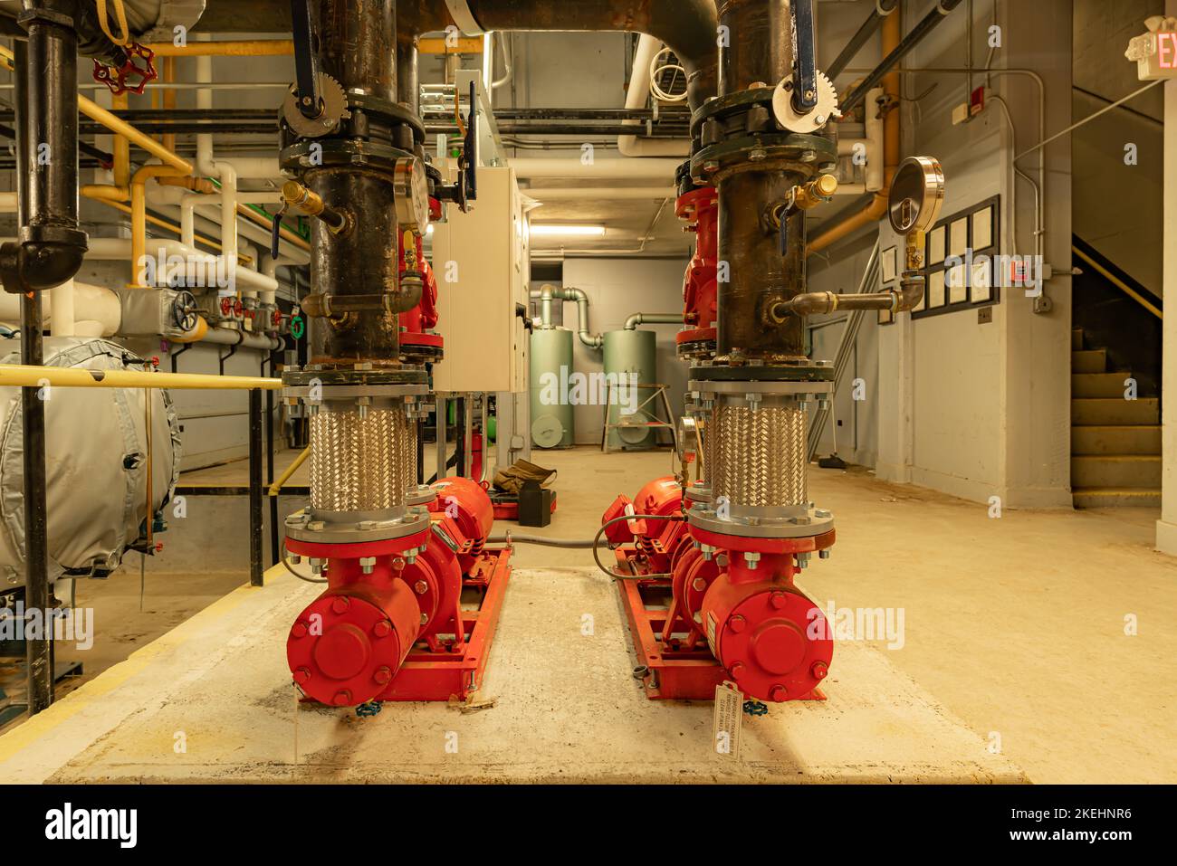L'interno di un vecchio e ben utilizzato locale caldaia con due grandi pompe meccaniche, tubi, valvole e altre attrezzature. Foto Stock