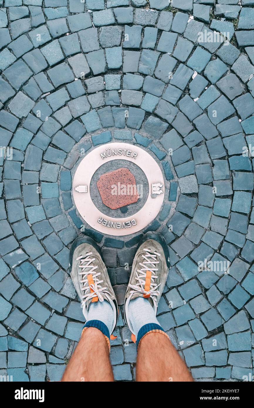 Un turista piedi sulle acciottolate vicino ad una pietra con l'iscrizione Munster in Germania Foto Stock