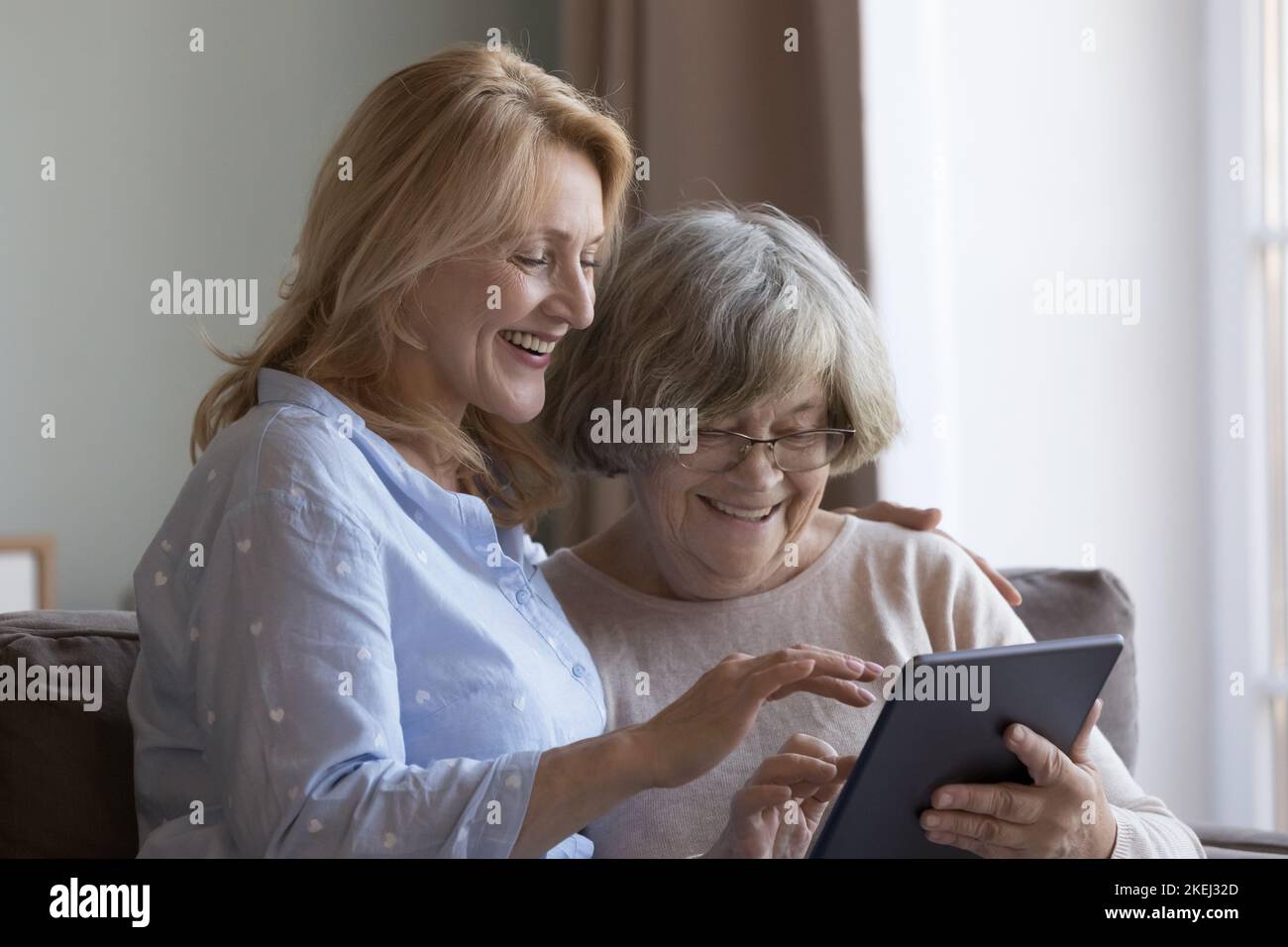 La donna matura aiuta la mamma anziana con l'uso di un tablet digitale Foto Stock