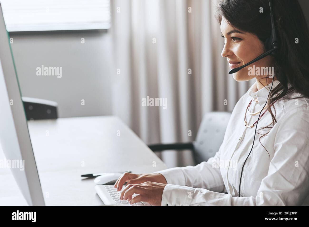 Assistenza affidabile per il supporto tecnico remoto. Un agente di supporto amichevole che lavora alla scrivania di un ufficio. Foto Stock