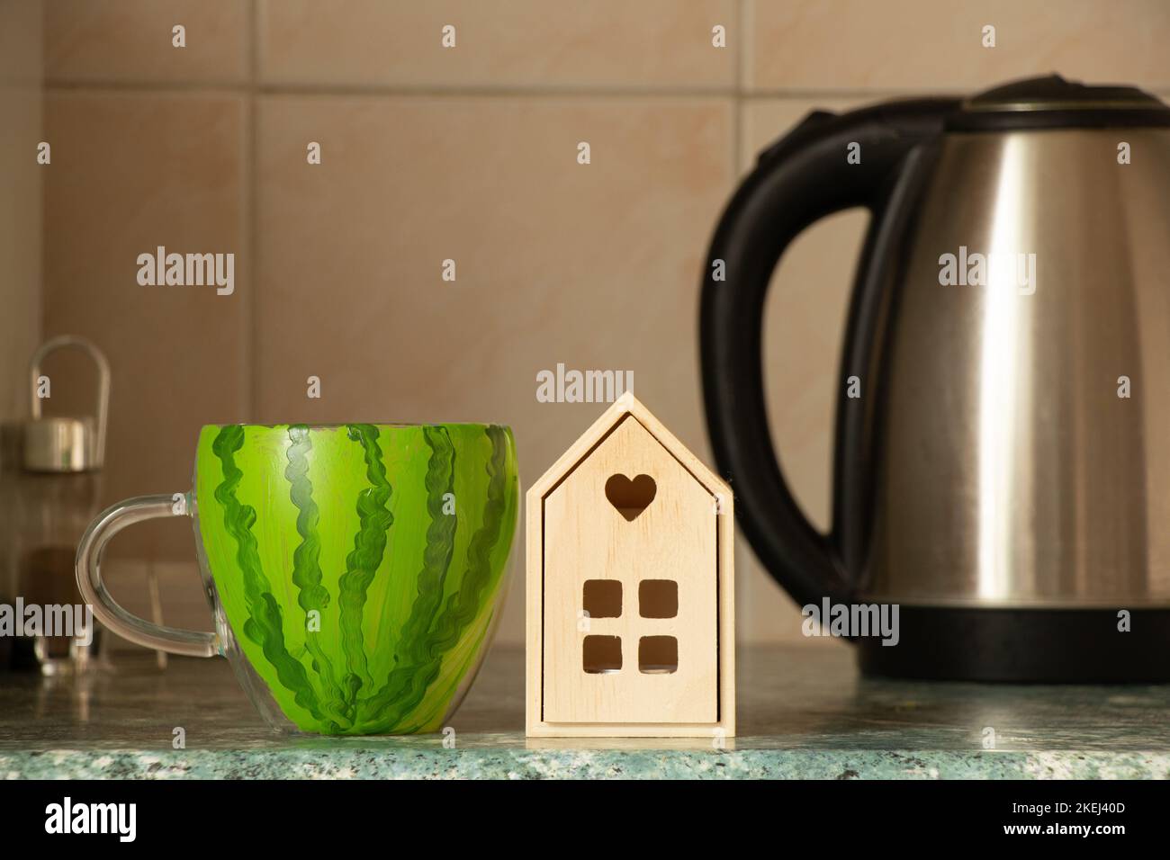 Una tazza con l'immagine di un anguria si trova su un tavolo in cucina vicino a una piccola casa e un bollitore in Ucraina in un appartamento, la liberazione di KH Foto Stock