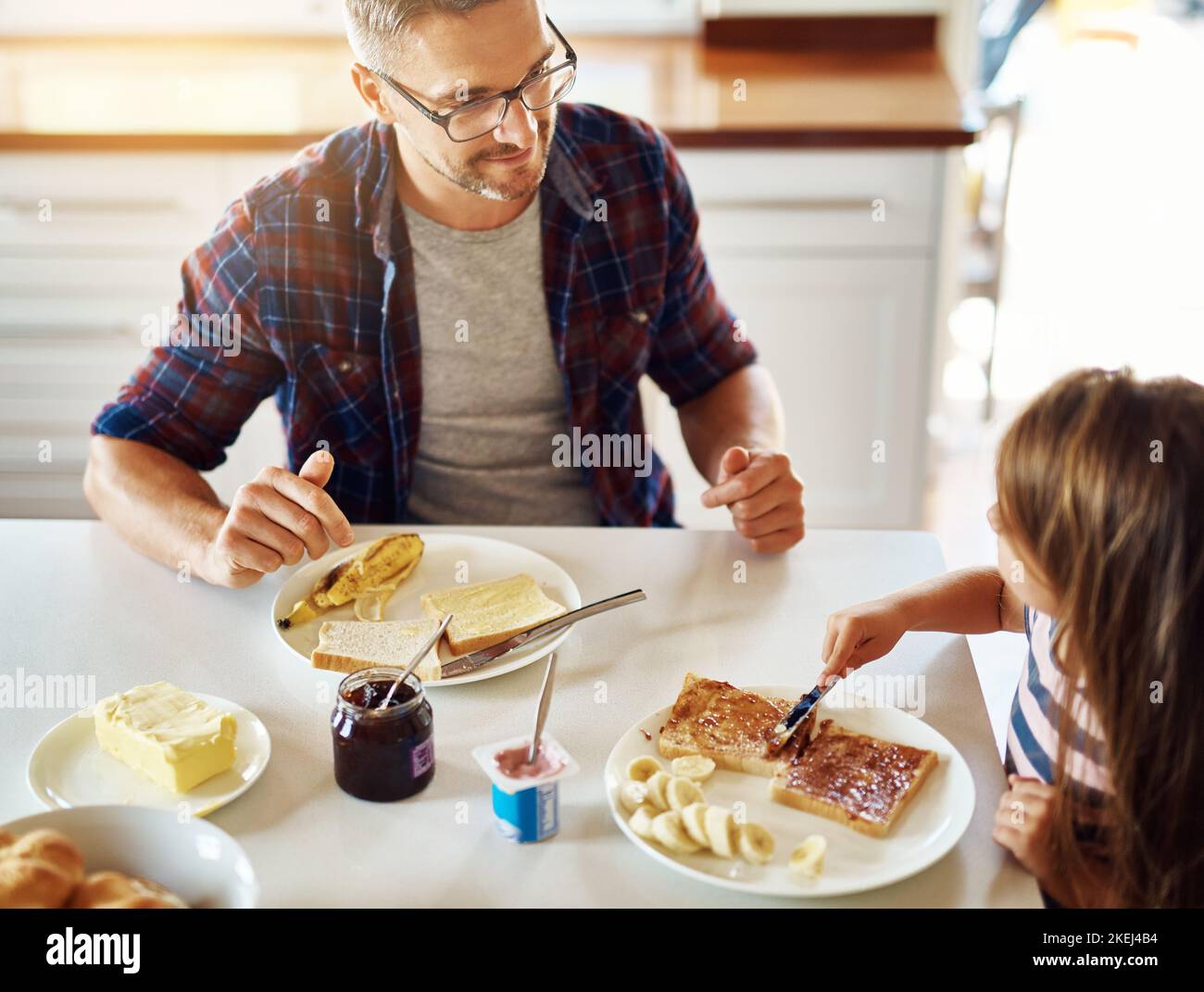 Vi godete la vostra colazione. Una ragazza adorabile che fa colazione con suo padre in cucina. Foto Stock