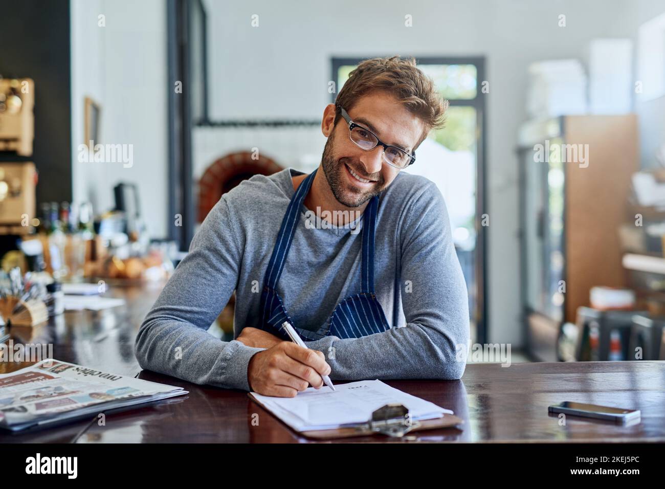 Il lavoro duro è un buon giovane proprietario di una caffetteria che fa un po' di documenti. Foto Stock