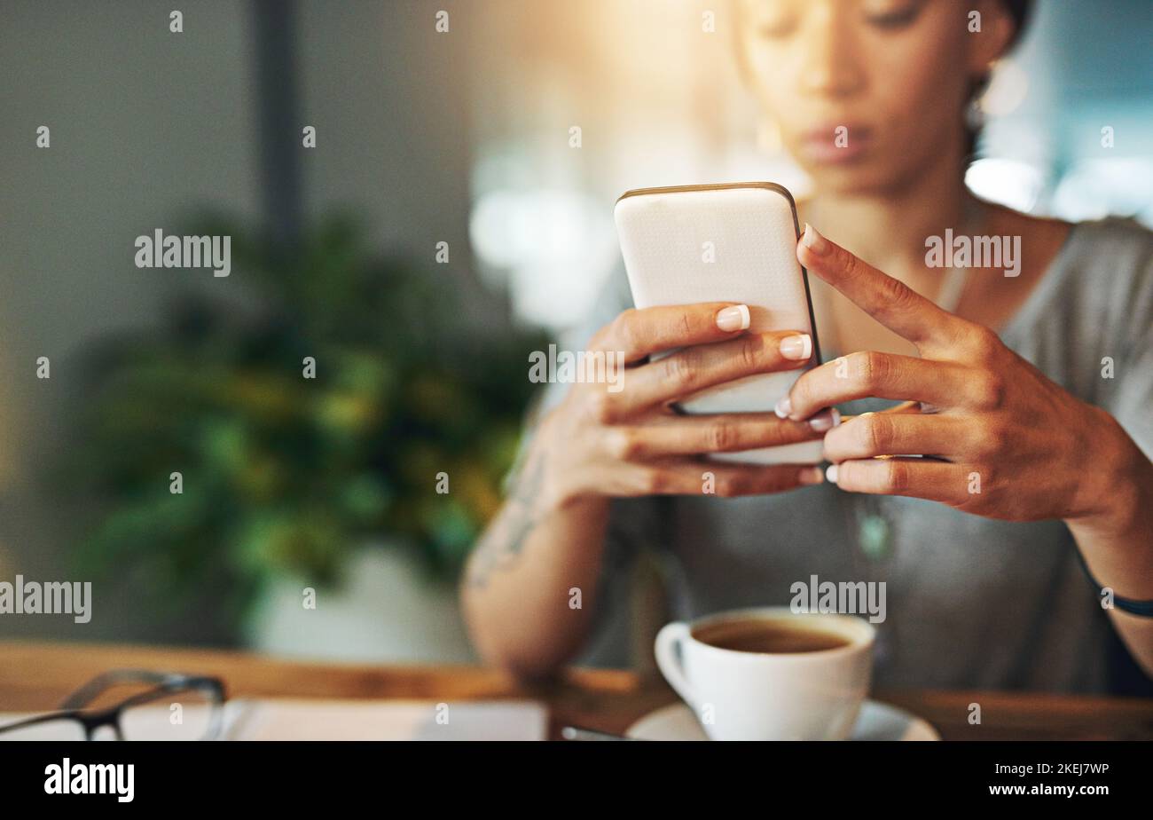 Fare affari in viaggio. Una giovane donna che invia un sms mentre lavora tardi nel suo ufficio. Foto Stock