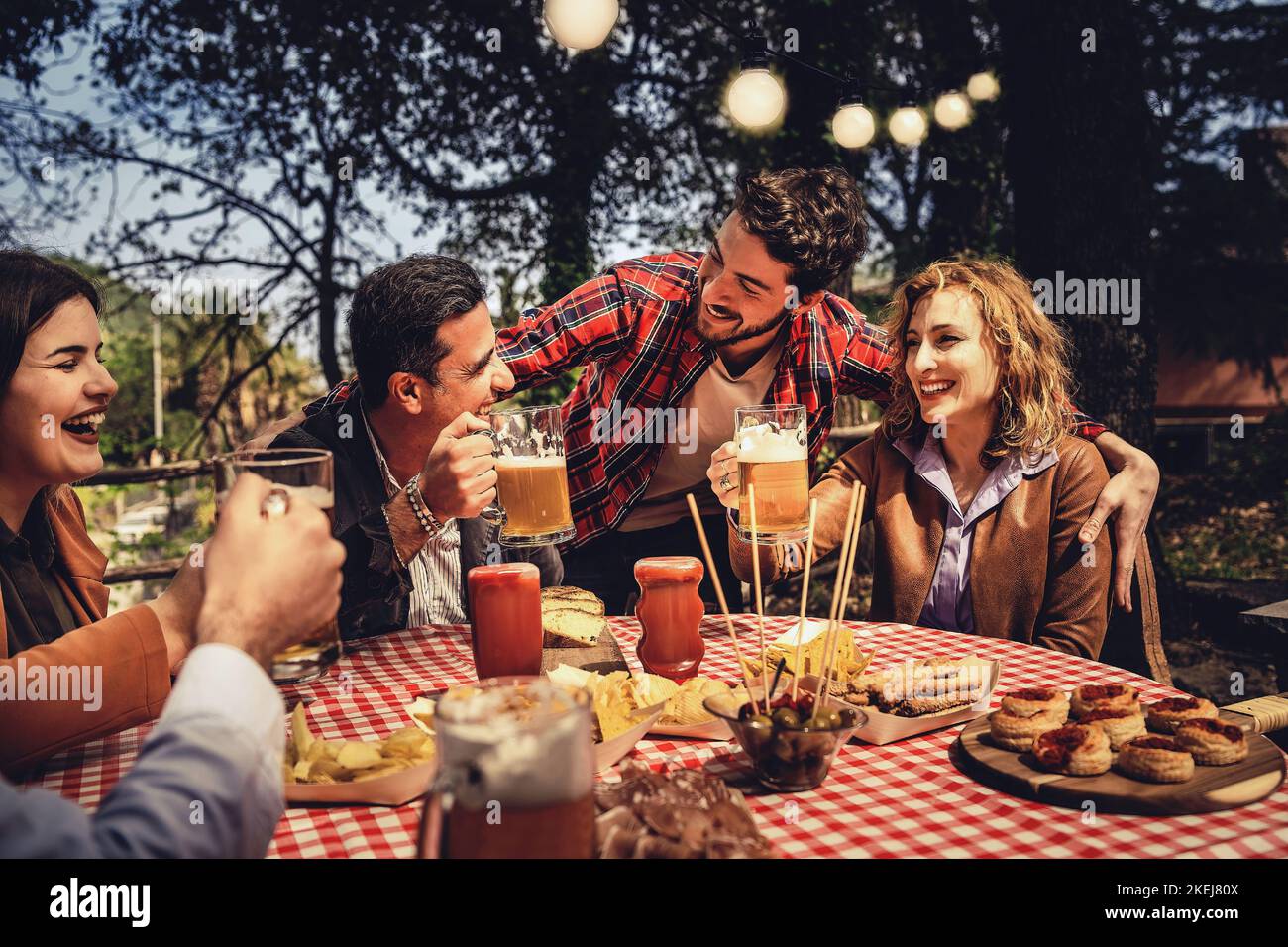 Gruppo di amici familiari a maglia stretta bere e mangiare insieme divertirsi in campagna nel fine settimana in una primavera crepuscolo - cibo, bevande, lifestyle con Foto Stock