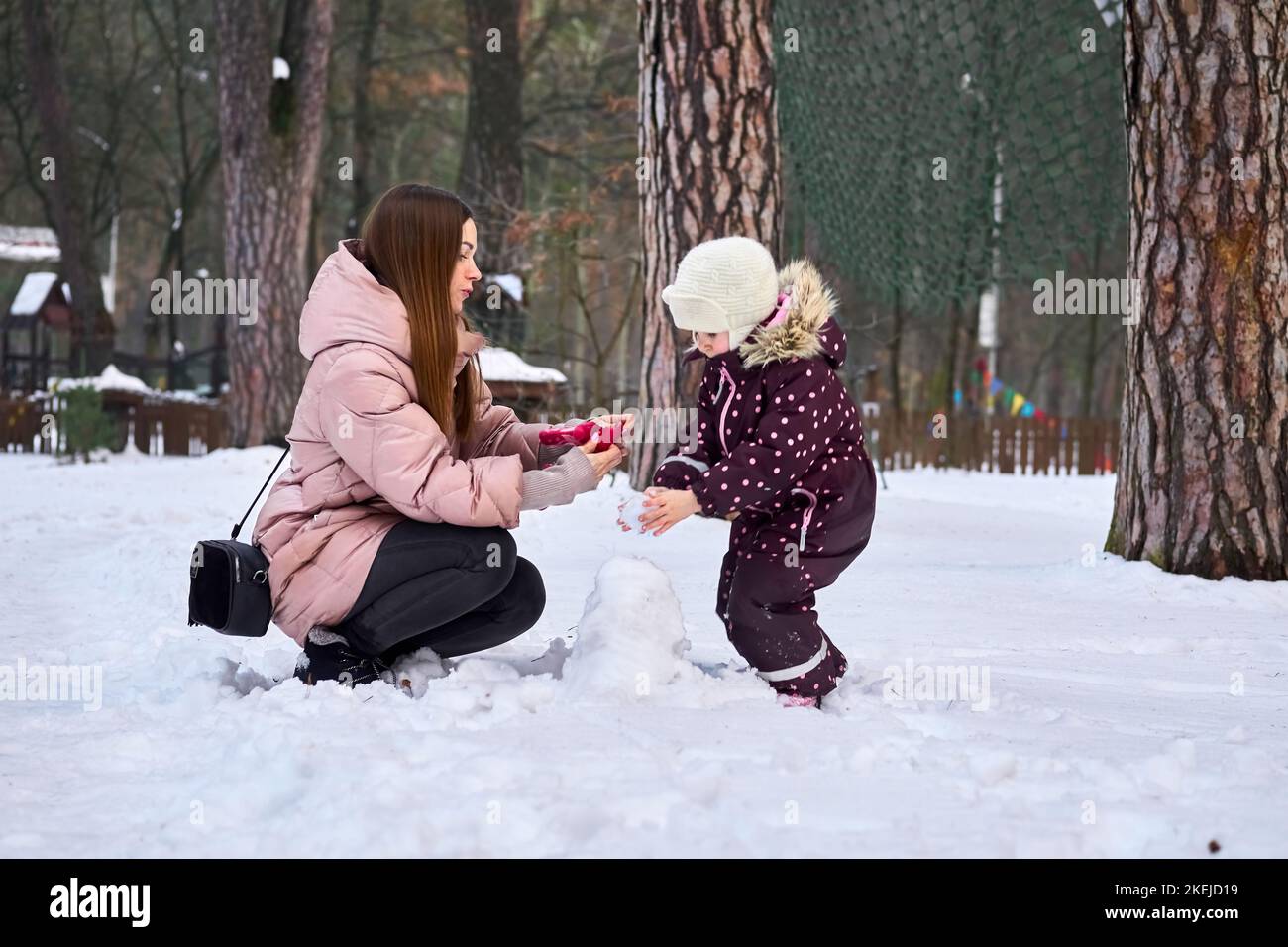 La madre premurosa mette i guanti sul suo bambino in una giornata invernale. Foto Stock