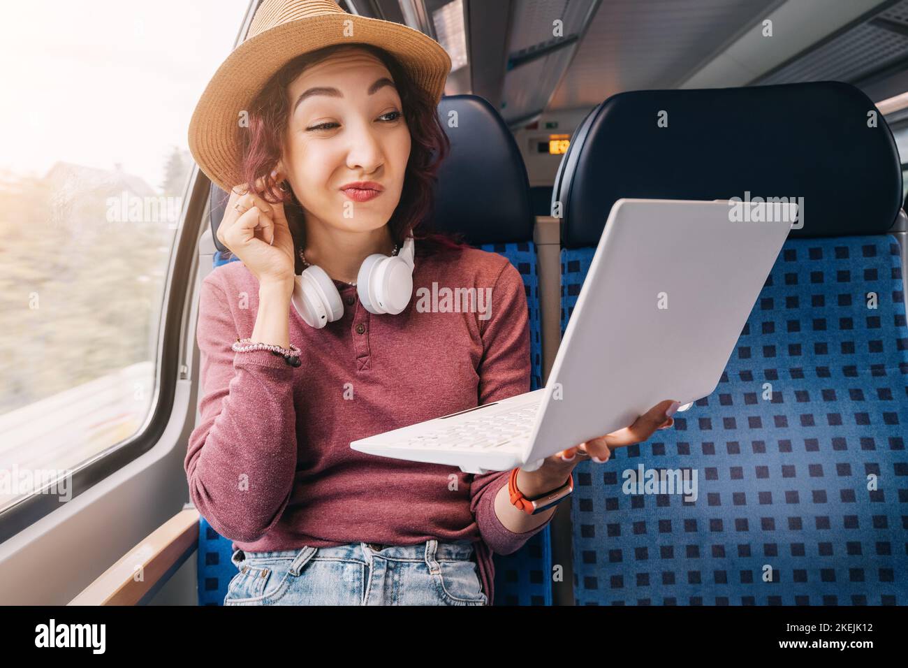 La ragazza trasmette informazioni personali a intrusi e hacker attraverso una rete Wi-Fi pubblica in treno. Frode e sicurezza della rete e del computer. Foto Stock