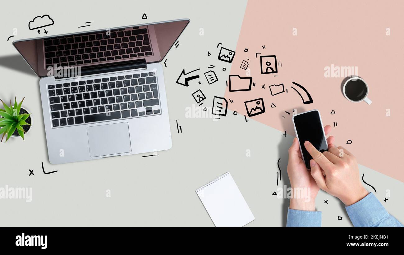 Una persona invia diversi file da uno smartphone a un computer portatile utilizzando la tecnologia wireless. Foto Stock