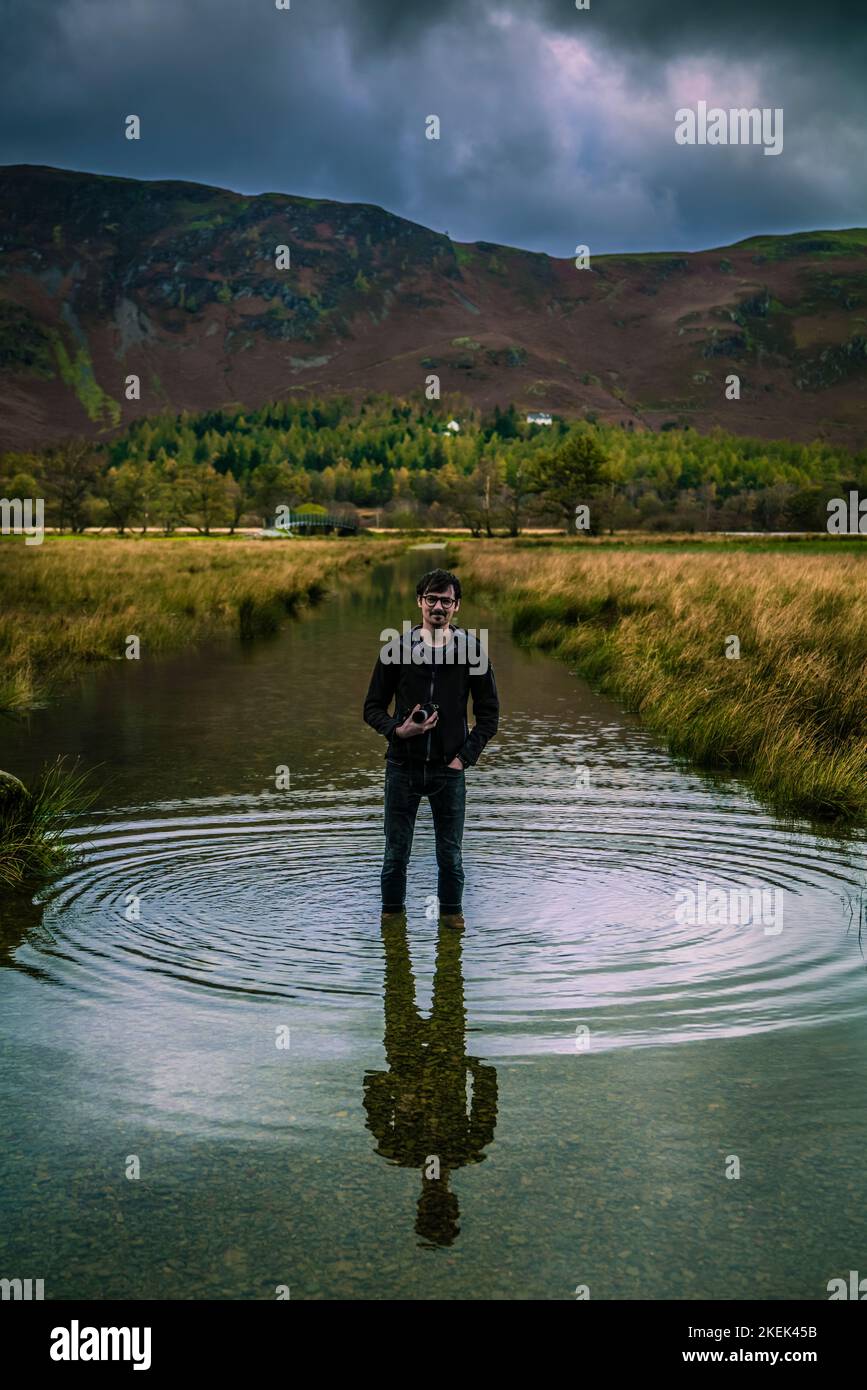 Fotografo maschile che si guadi per ottenere il miglior scatto, Grange a Borrowdale, English Lake District. Foto Stock