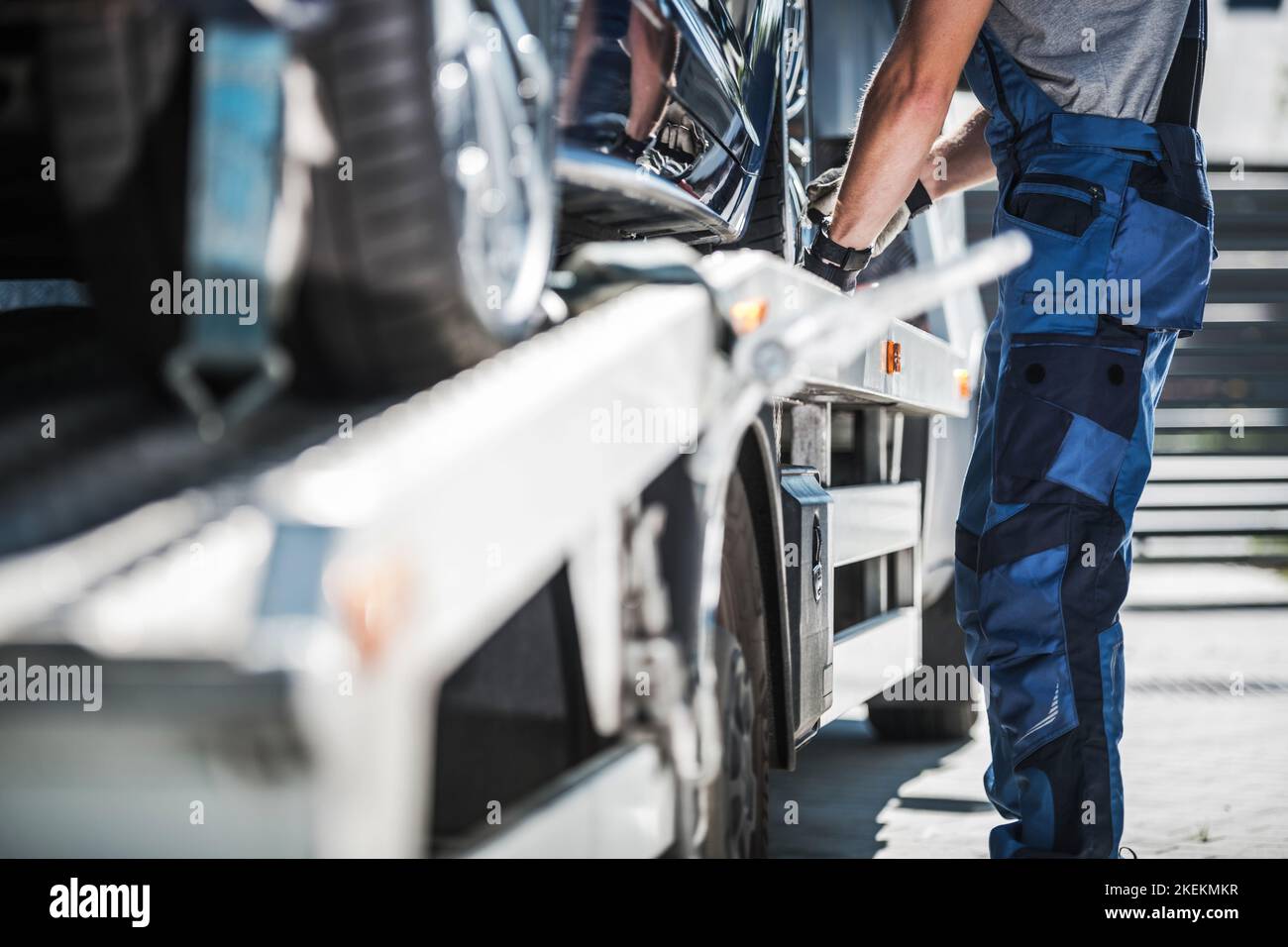 Lavoratore repo professionale che fissa l'auto su un autocarro da traino. Foto Stock