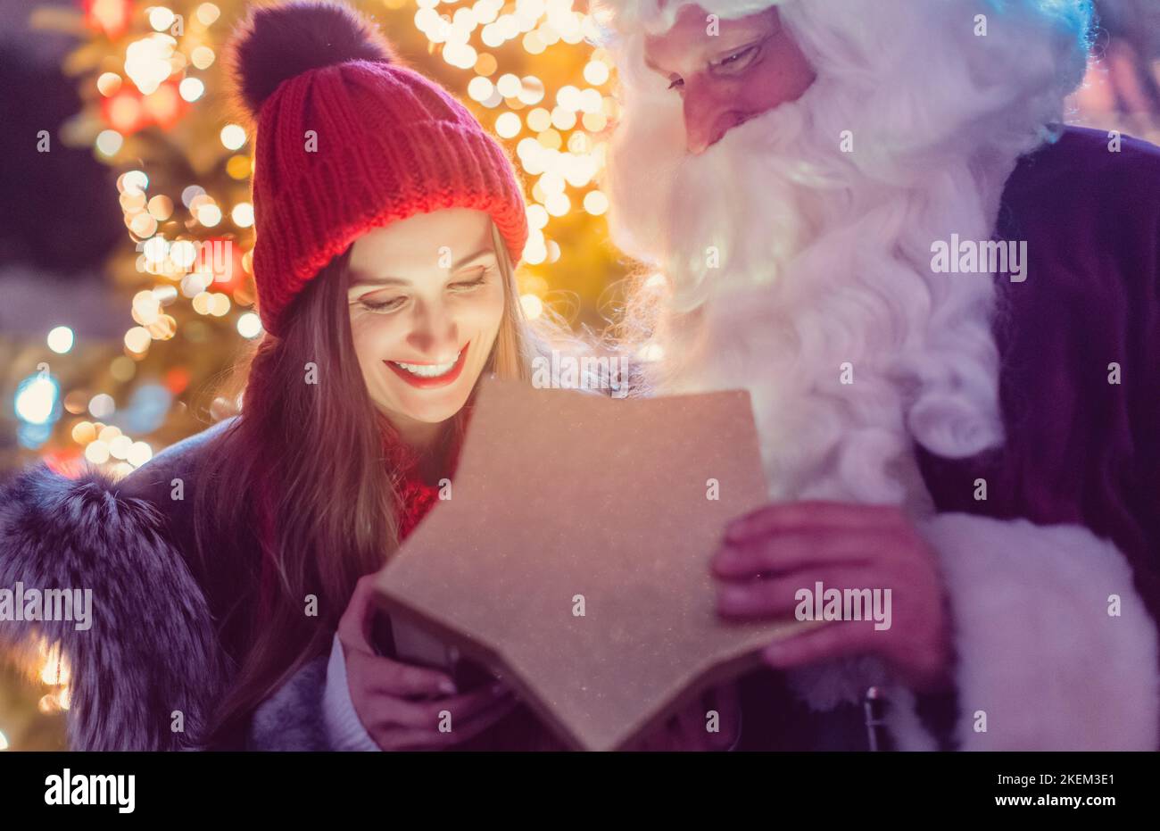 Babbo Natale che dà regali davanti all'albero di Natale Foto Stock