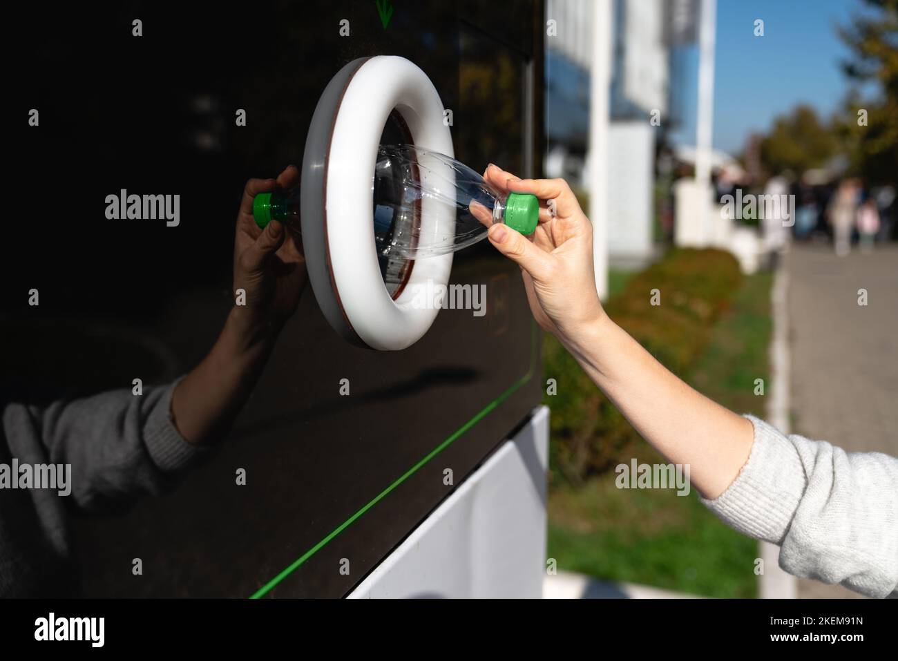 Donna utilizza una macchina self-service per ricevere bottiglie di plastica usate e lattine su una strada cittadina Foto Stock