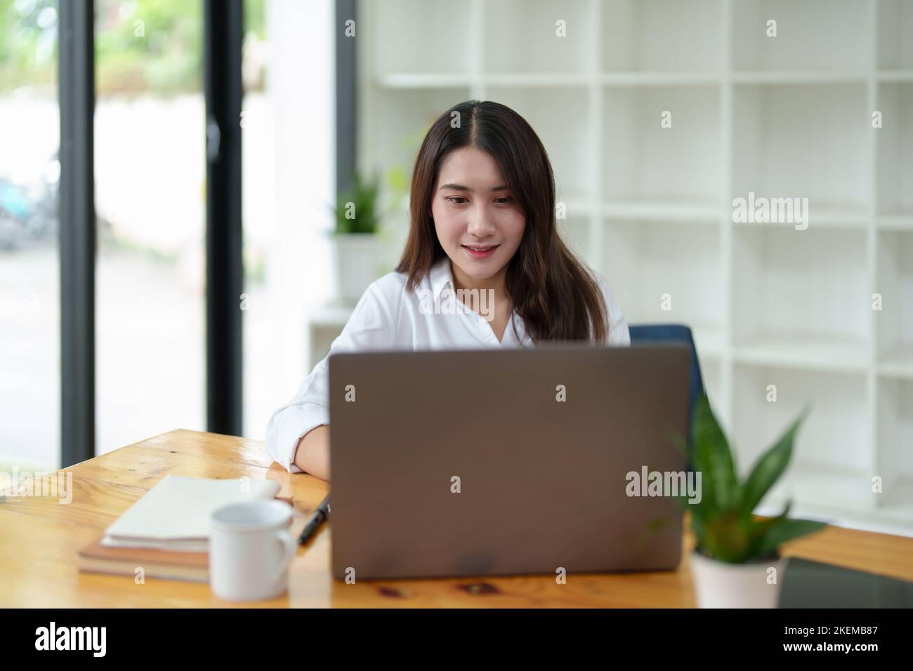 Ritratto di una bella donna asiatica d'affari al lavoro scrivania ufficio con computer portatile in ufficio Foto Stock