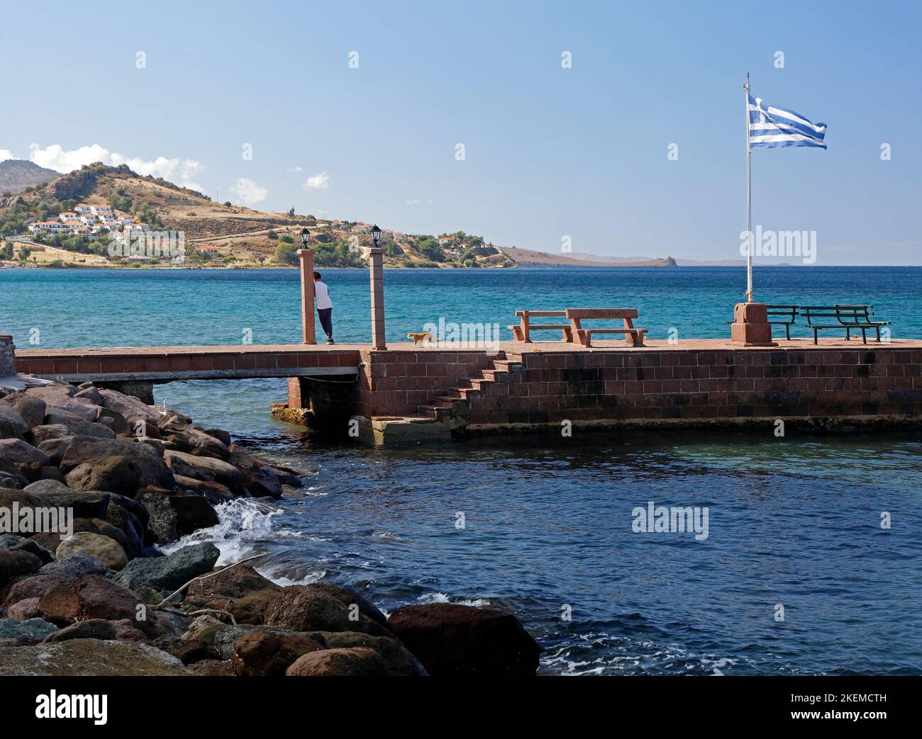 Giovane ragazzo e gatto zenzero sul molo a Petra, Lesbos isole scene. Ottobre 2022. Autunno Foto Stock