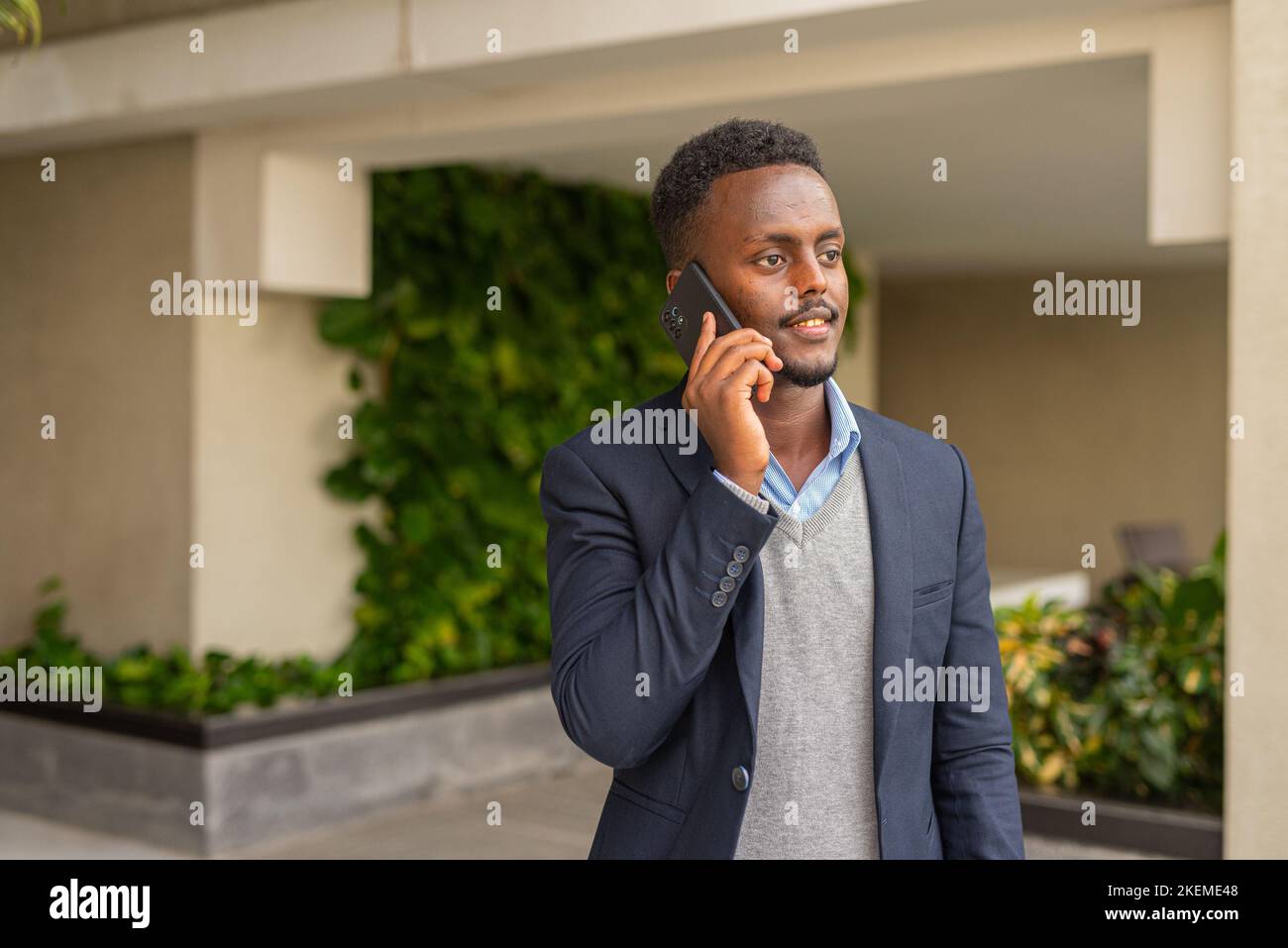Ritratto di bell'uomo d'affari africano nero che indossa la tuta e parla al telefono Foto Stock