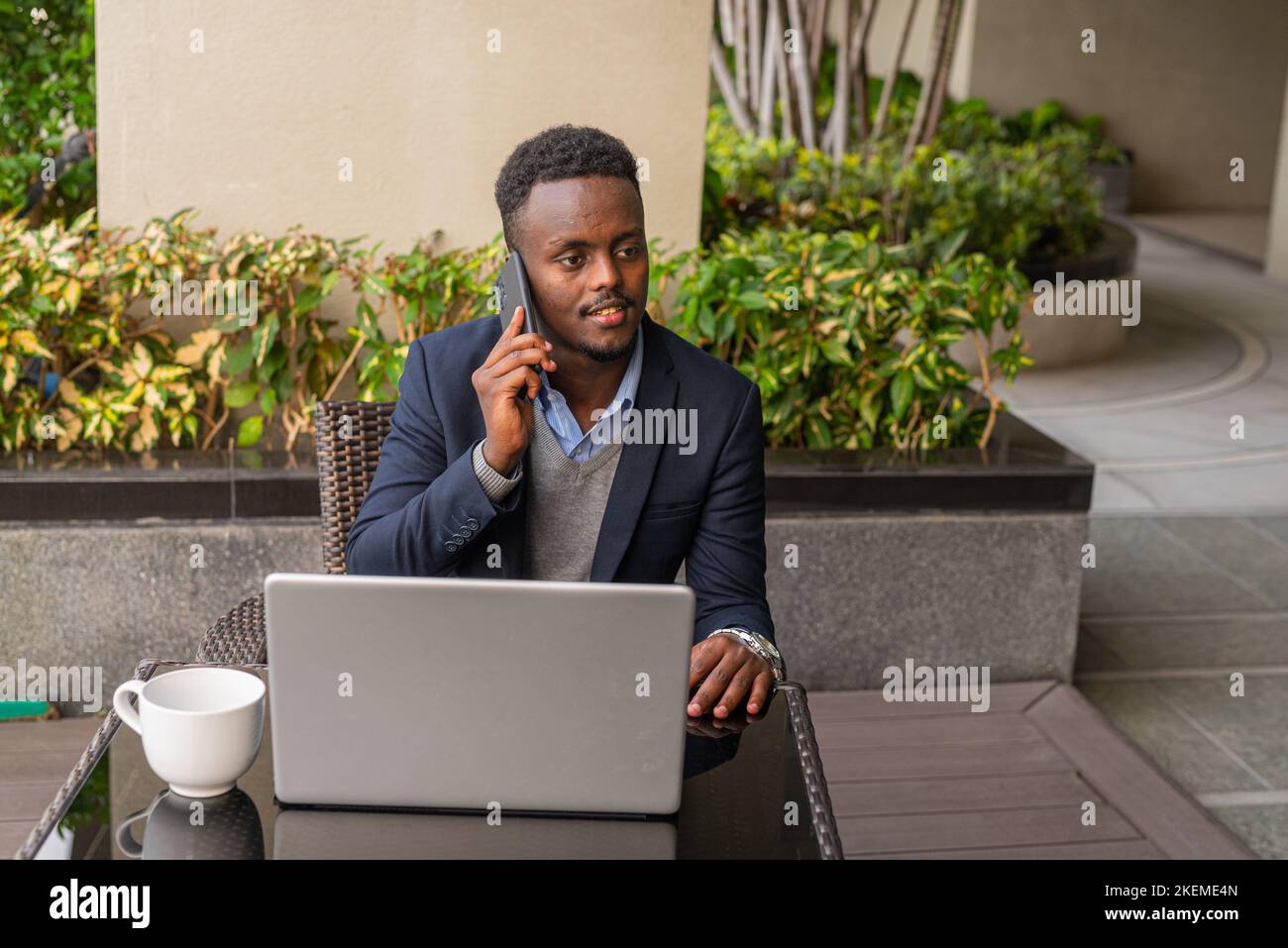 Ritratto di bell'uomo d'affari africano nero che indossa la tuta e utilizza un computer portatile Foto Stock
