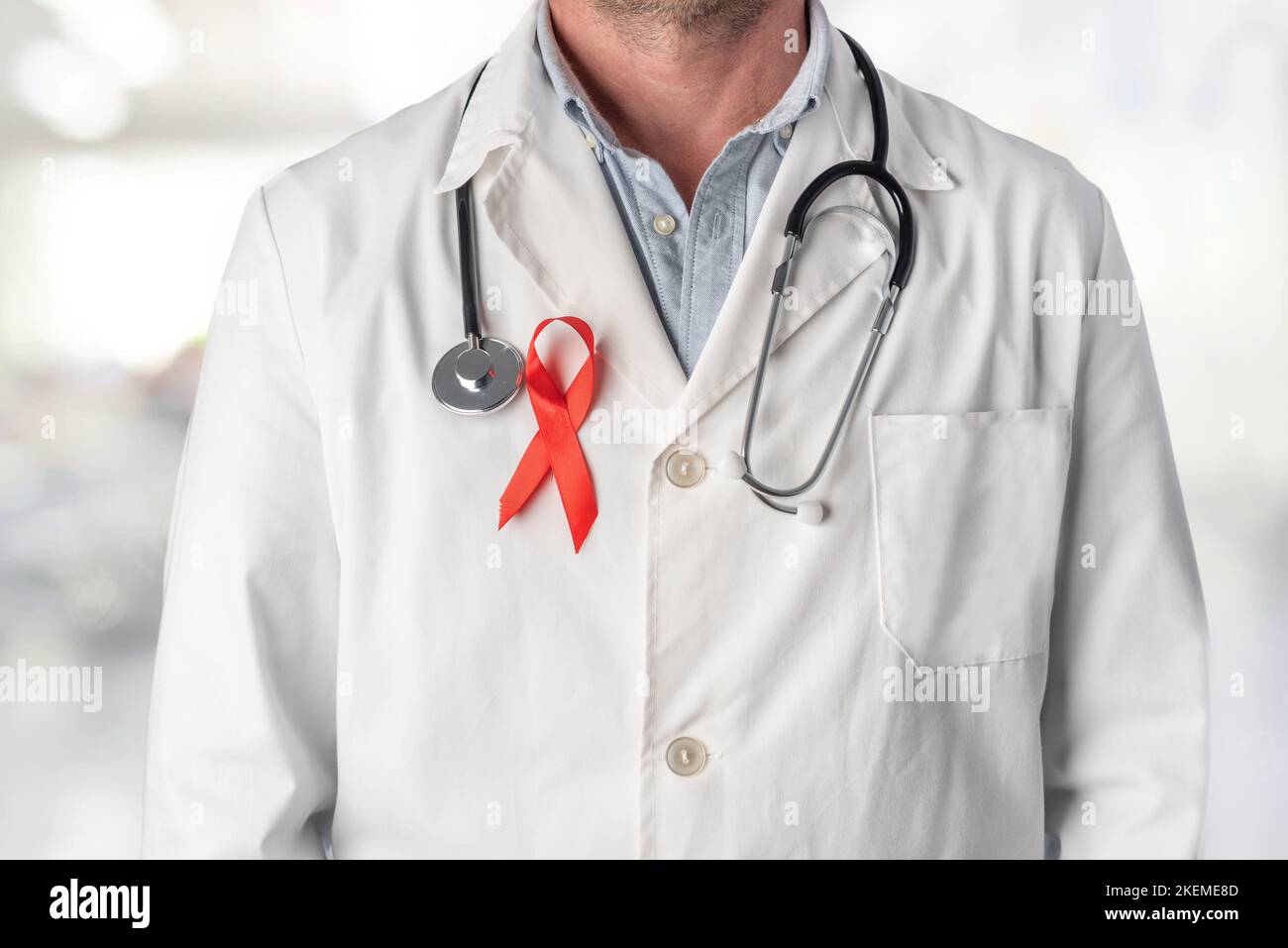 Medico che indossa un nastro rosso sul petto, simbolo della Giornata Mondiale contro l'AIDS. Supporto dal personale sanitario alle persone affette da hiv. Prevenzione e lotta contro il Foto Stock